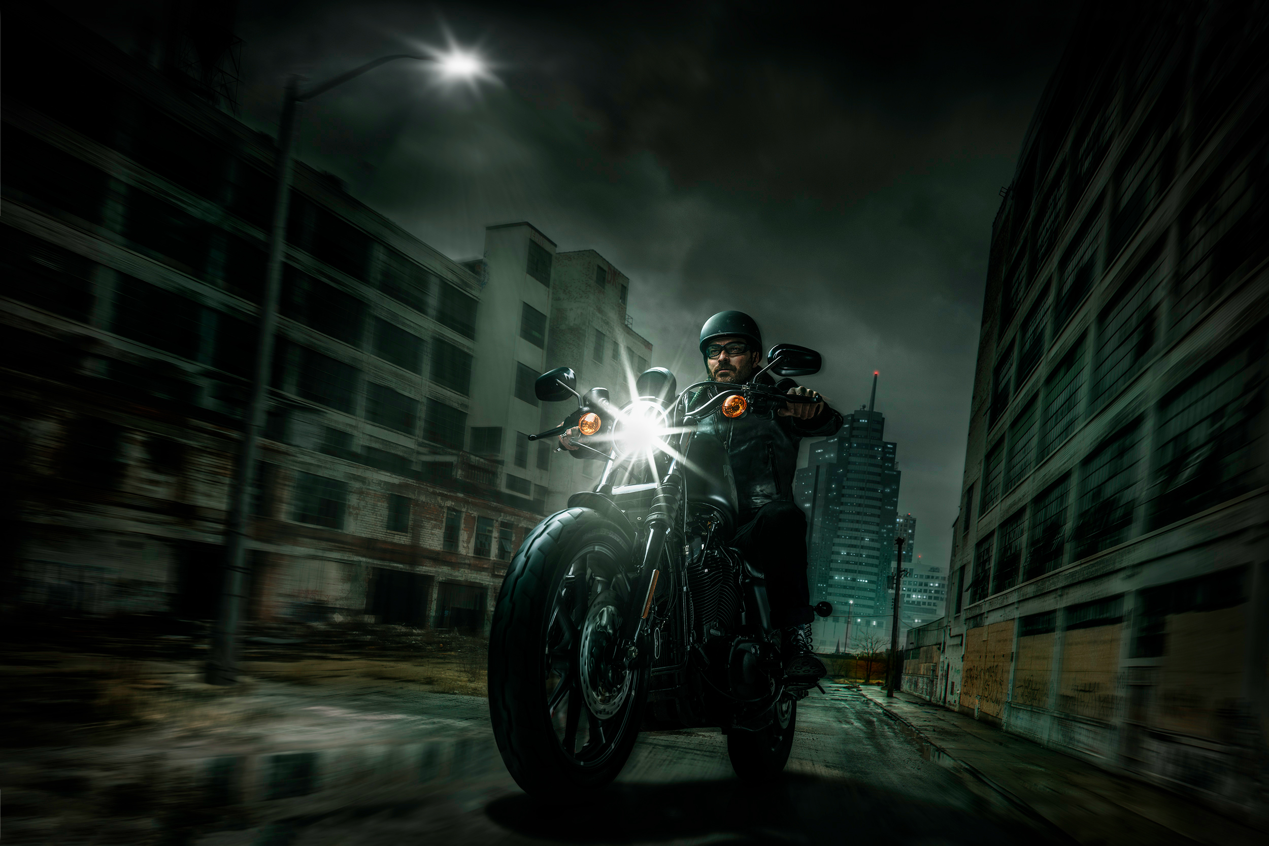 Man riding a Harley Davidson motorcycle in a city HD Wallpaper