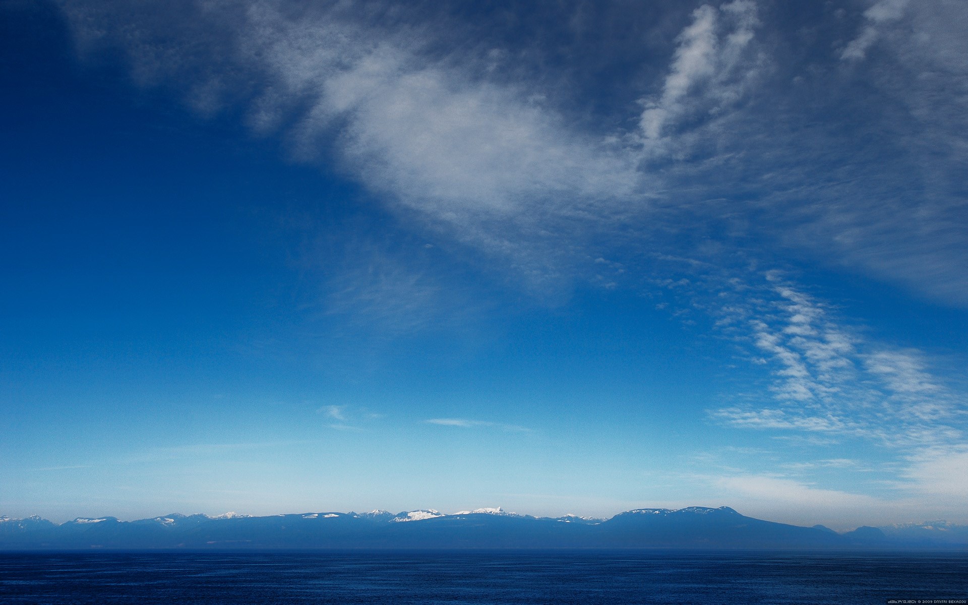 Vast blue sky over ocean and snow-capped mountains HD Wallpaper