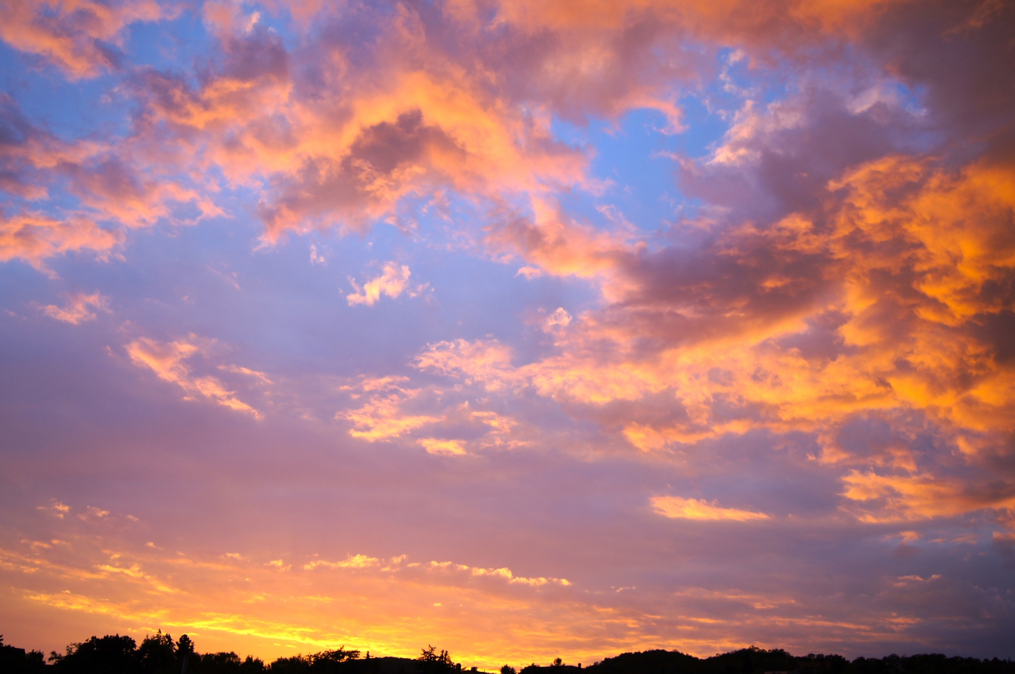 Sunset clouds over silhouetted trees and hills HD Wallpaper