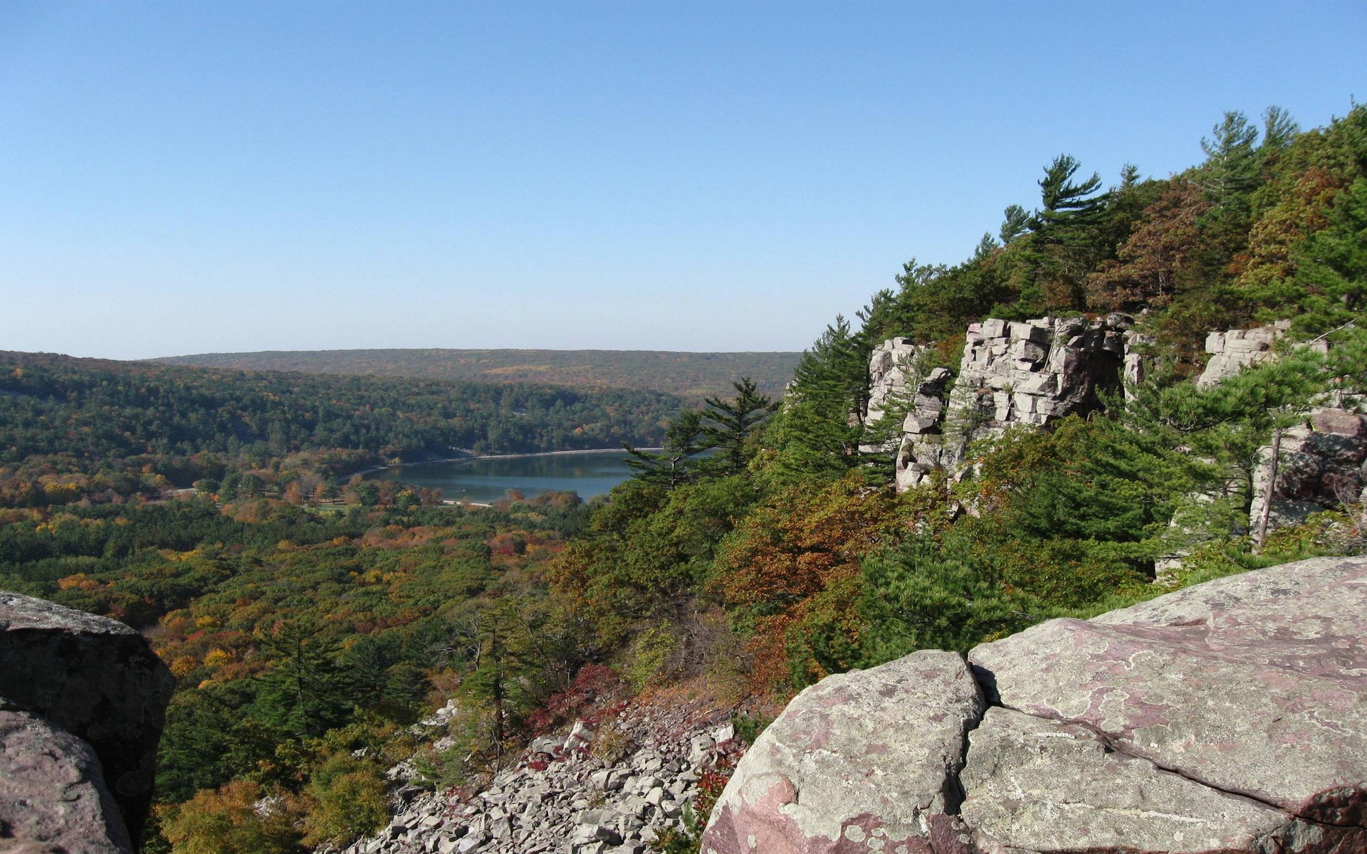 Rocky cliff overlooking a forest and lake HD Wallpaper