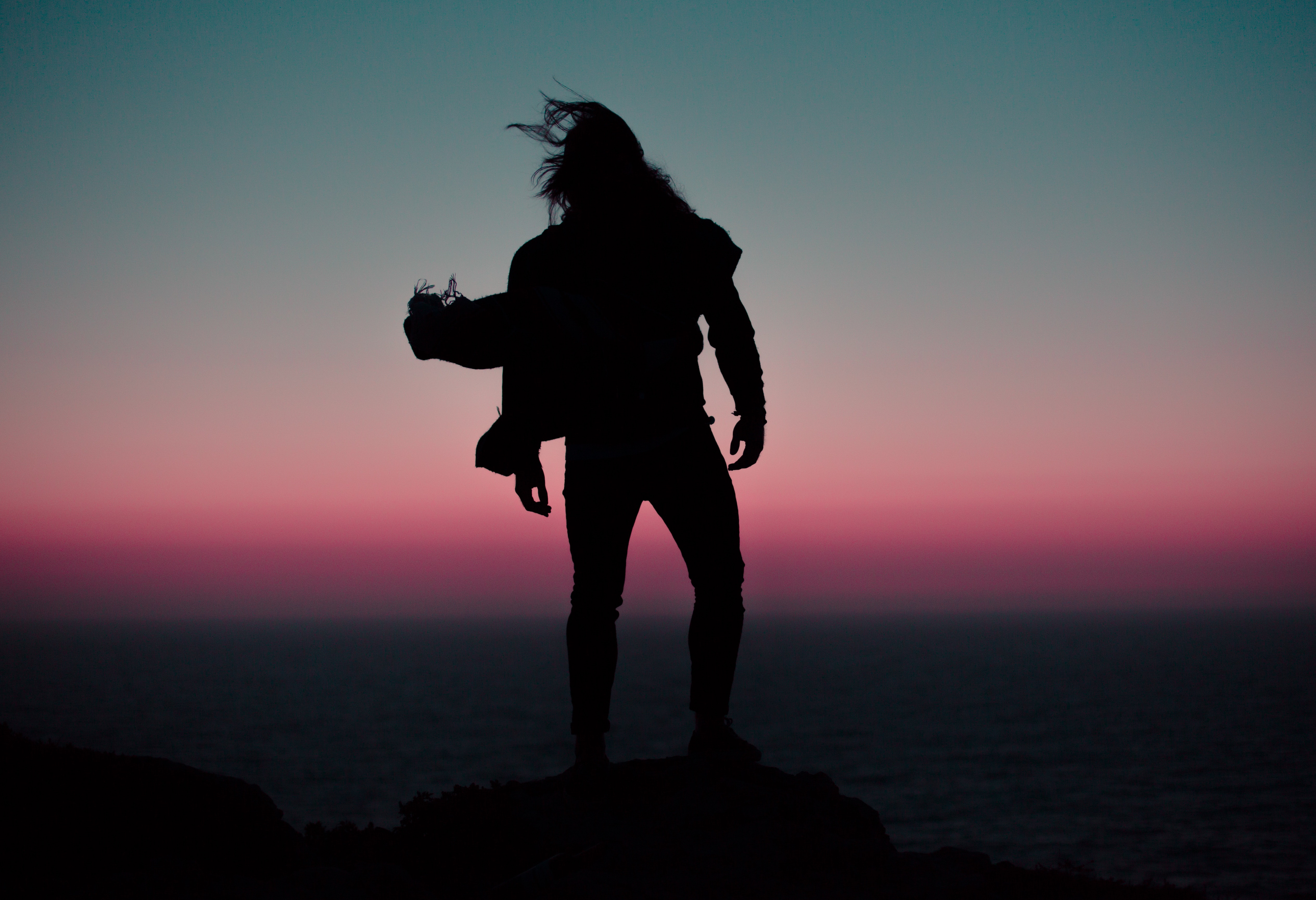 Silhouette of a man on a cliff at sunset HD Wallpaper