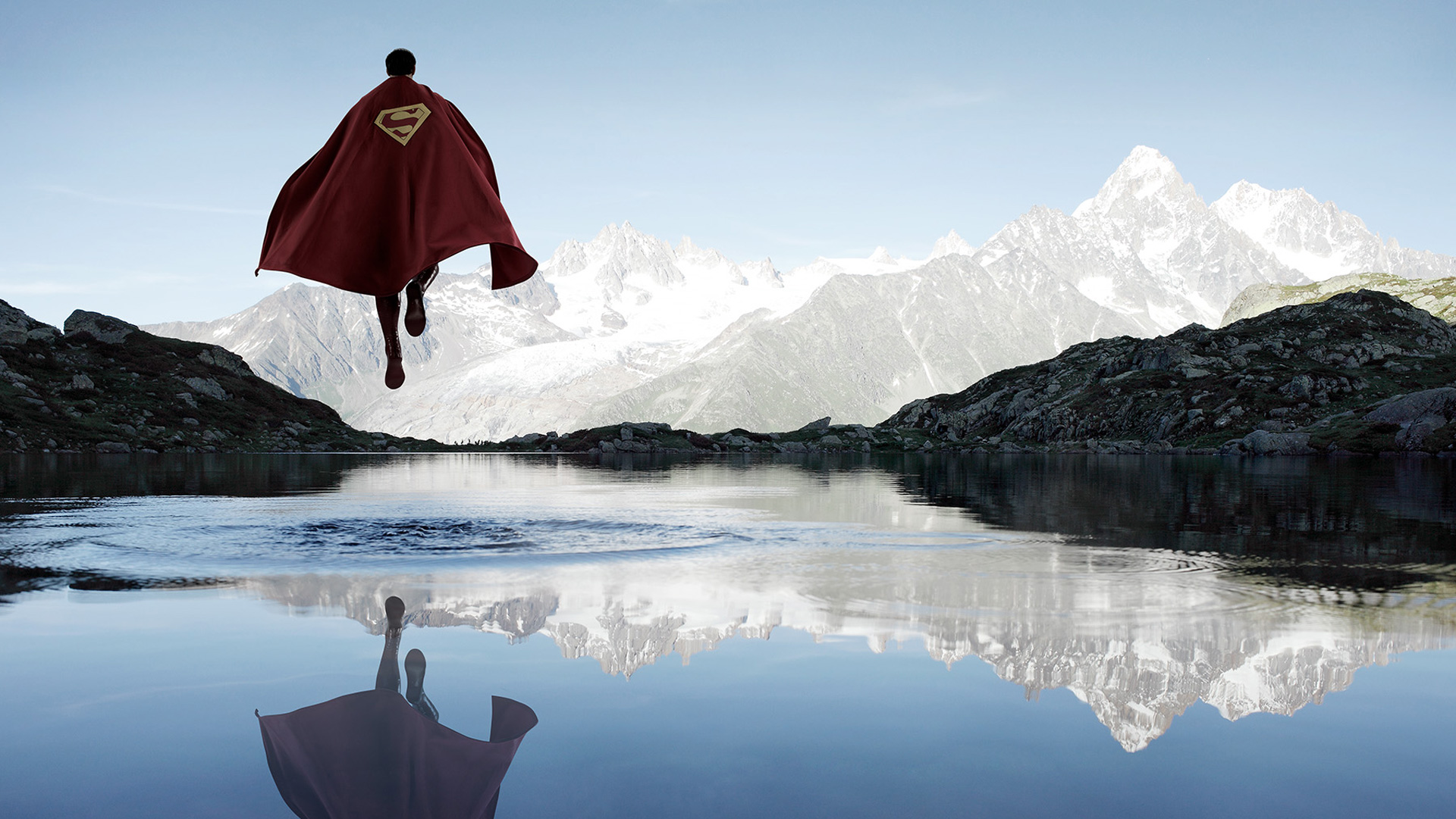Superman flying over a mountain lake HD Wallpaper