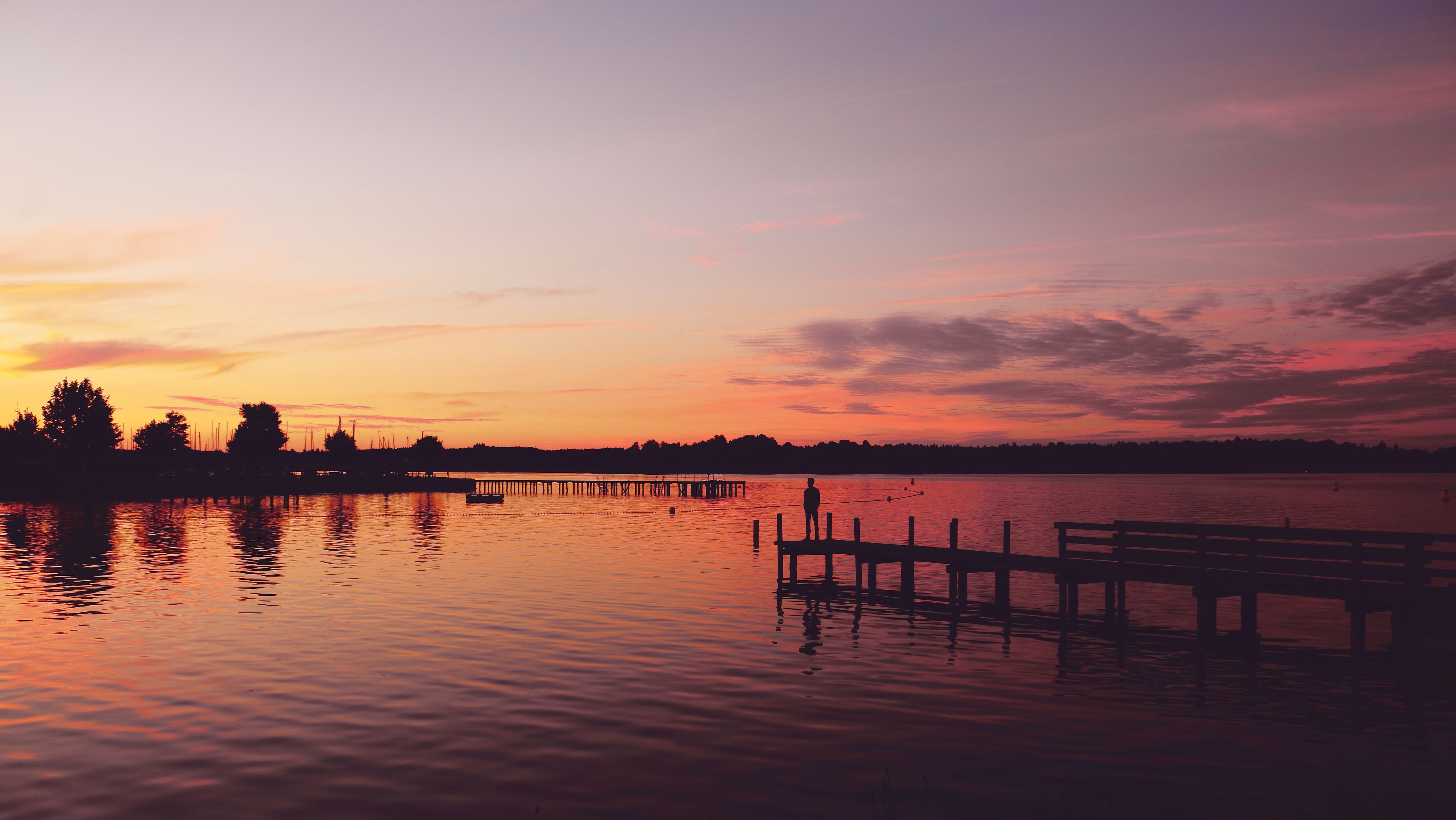 Man standing on a pier at sunset HD Wallpaper