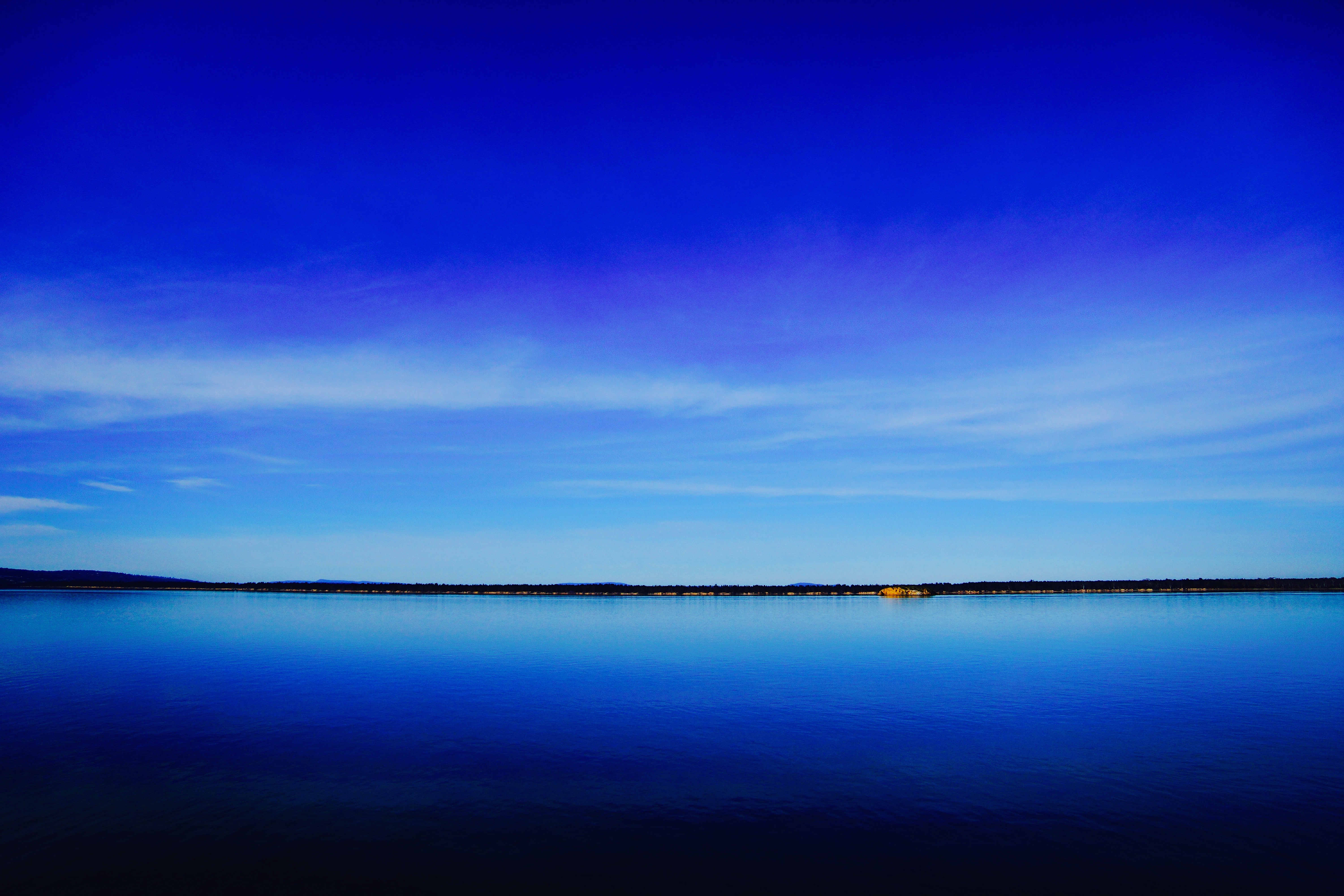 Vast blue lake under a bright blue sky HD Wallpaper