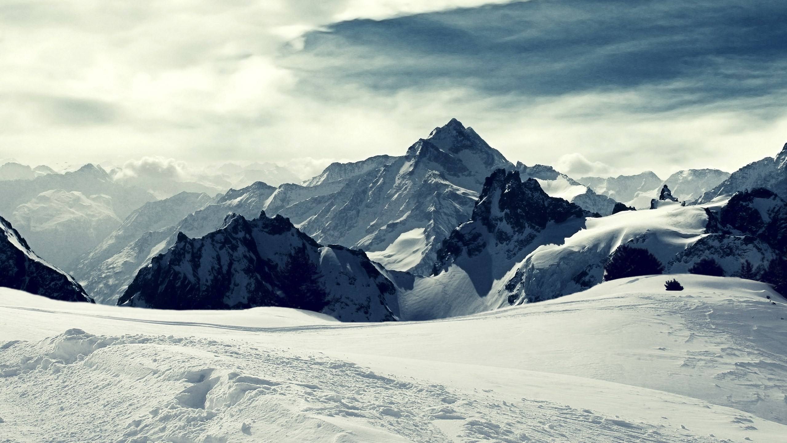 Snowy mountain range under a cloudy sky HD Wallpaper