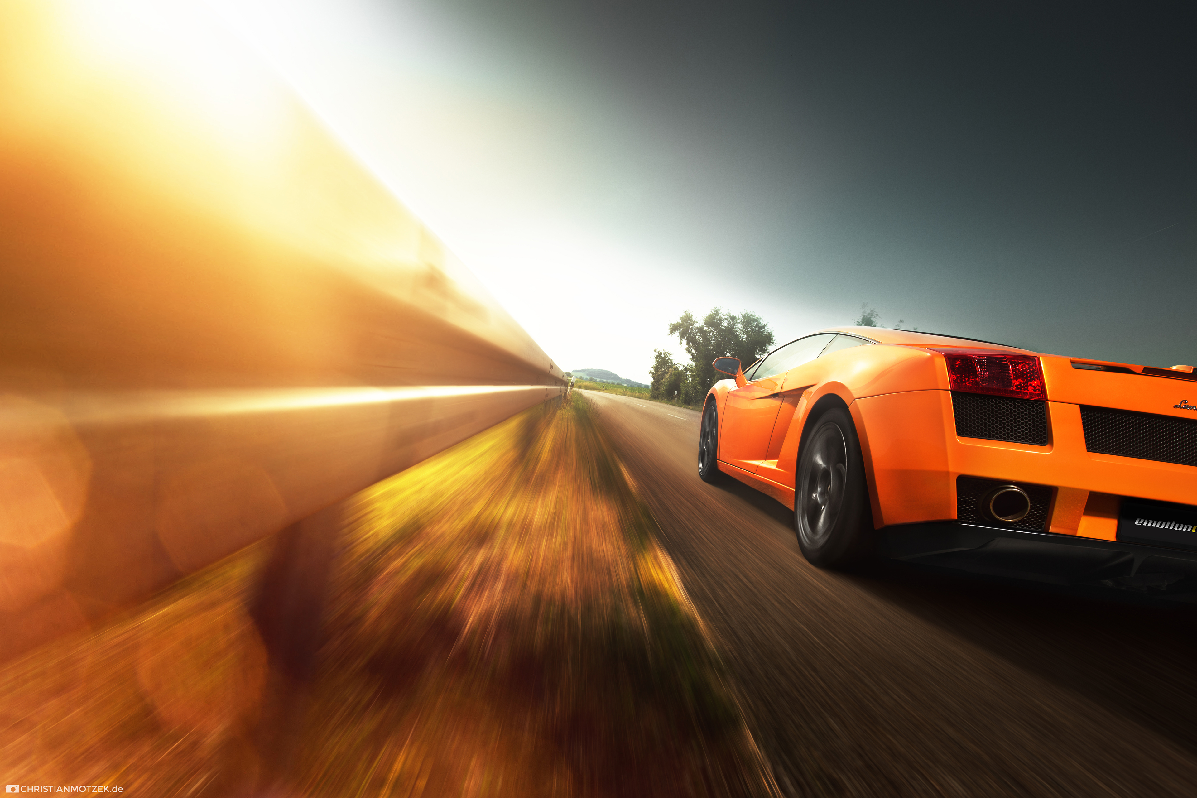 Orange Lamborghini driving on a road HD Wallpaper