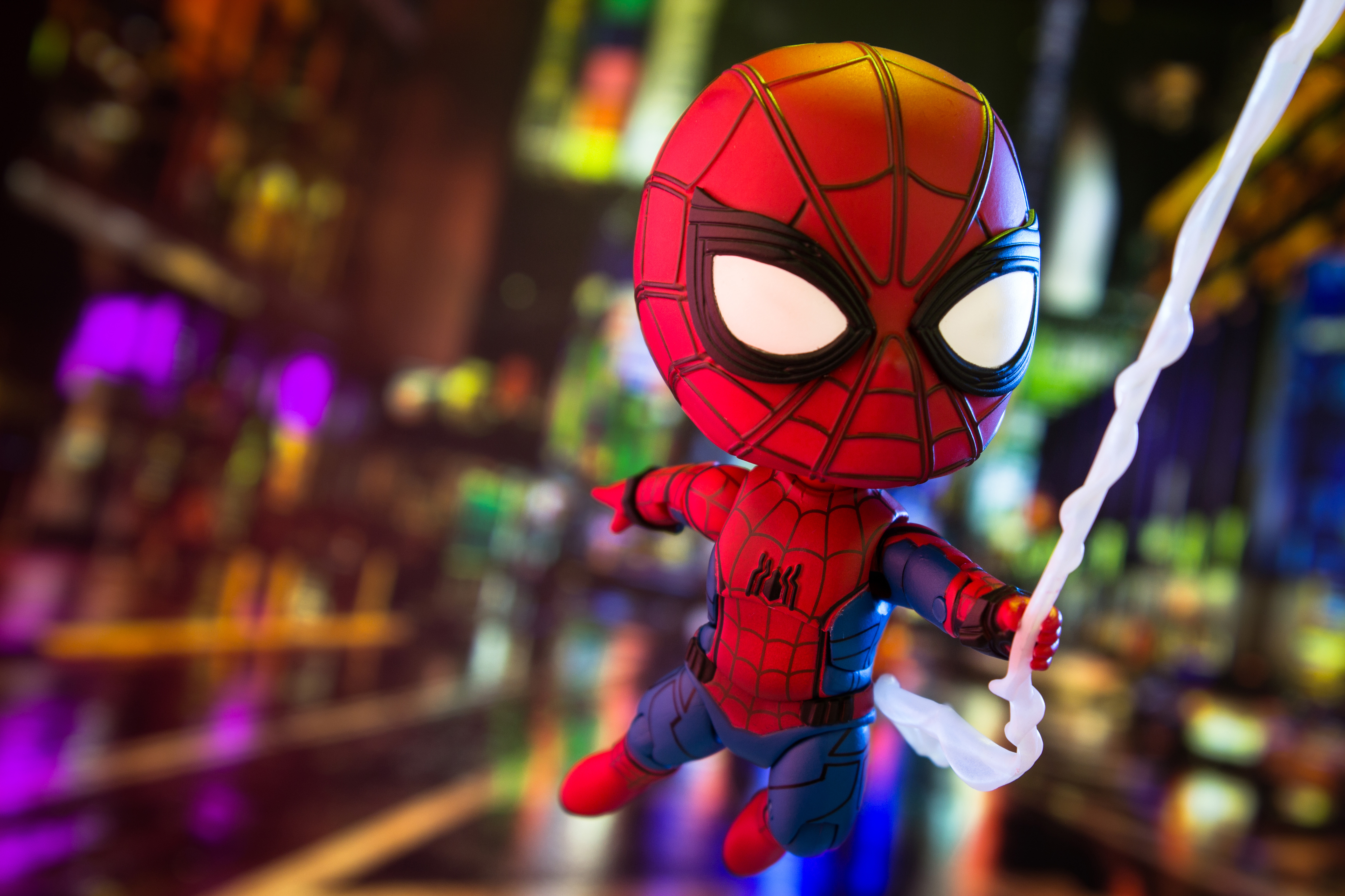 Spider-Man toy with web in blurry city background HD Wallpaper