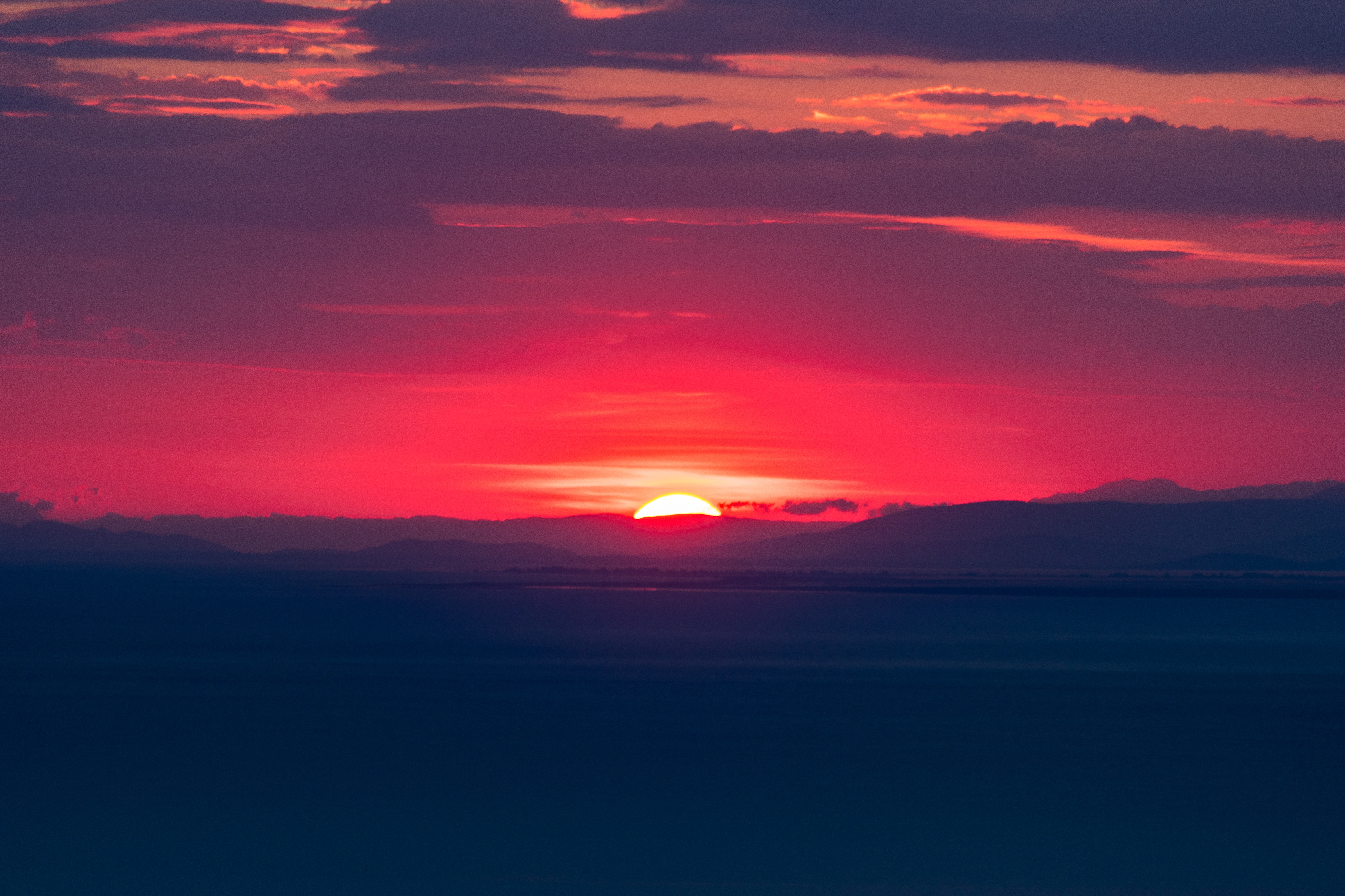 Vibrant sunset over mountains and water HD Wallpaper