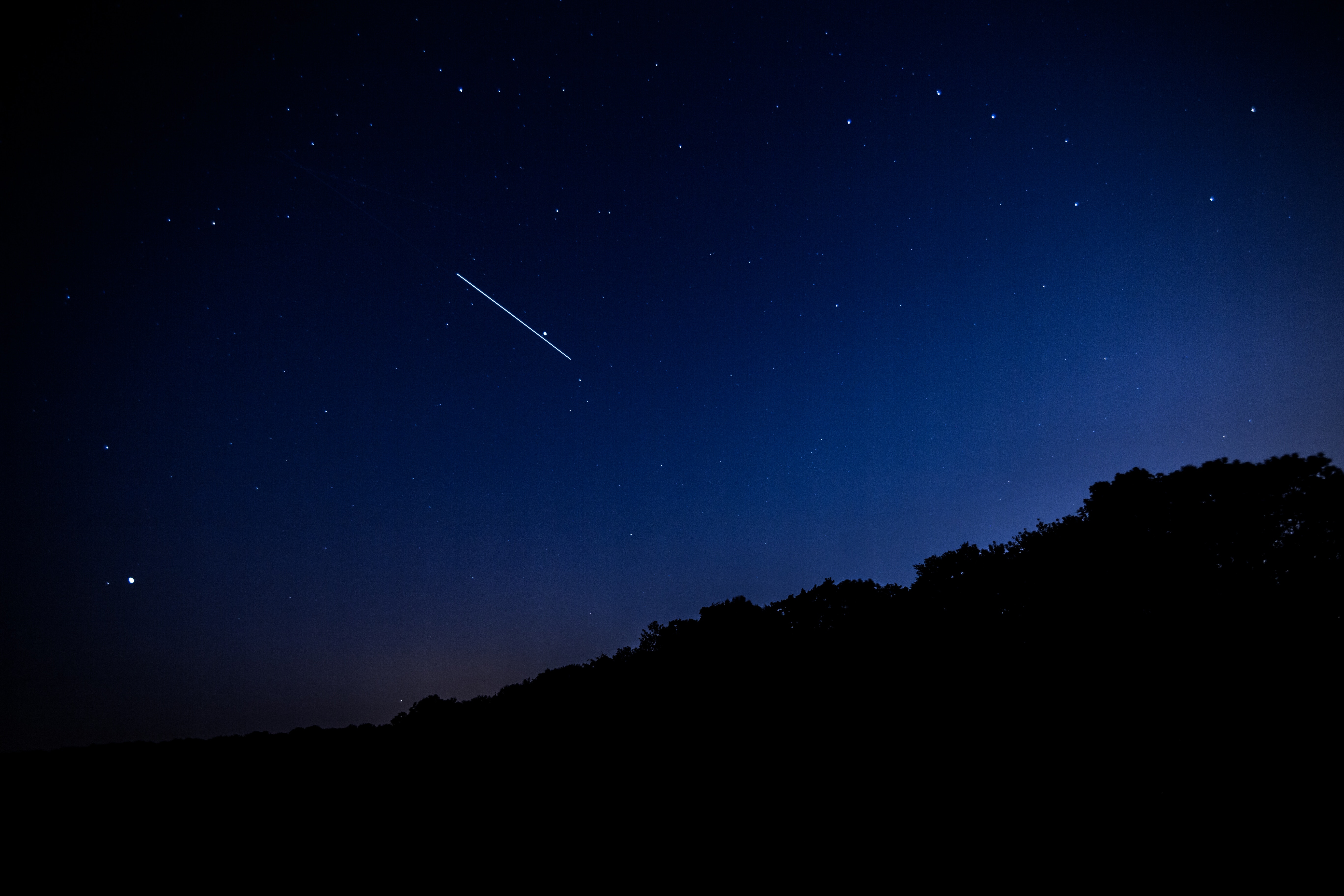 Shooting star in the night sky over a hill HD Wallpaper