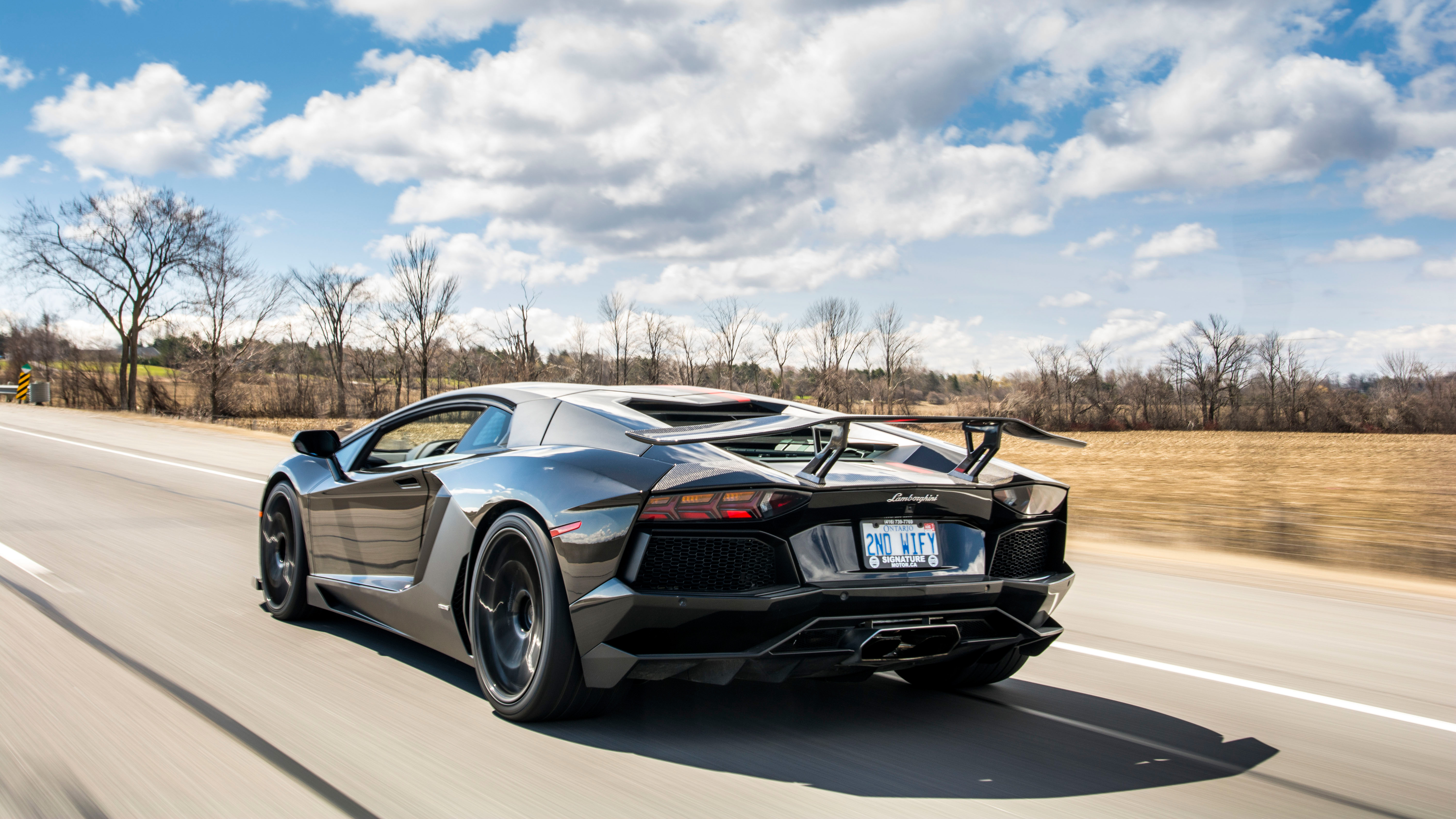 Lamborghini Aventador driving on a road HD Wallpaper