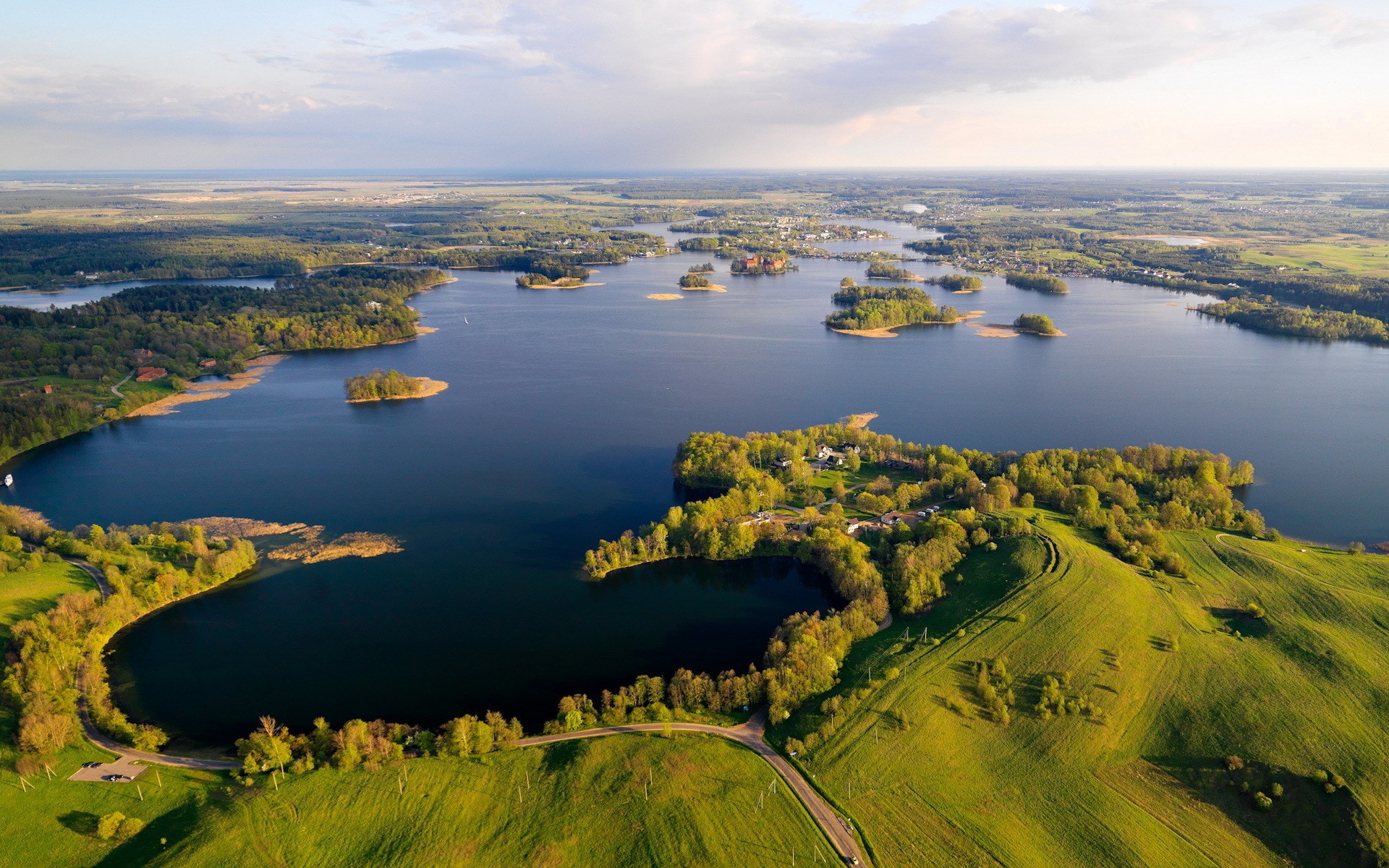 Aerial view of a lake with islands and green hills HD Wallpaper