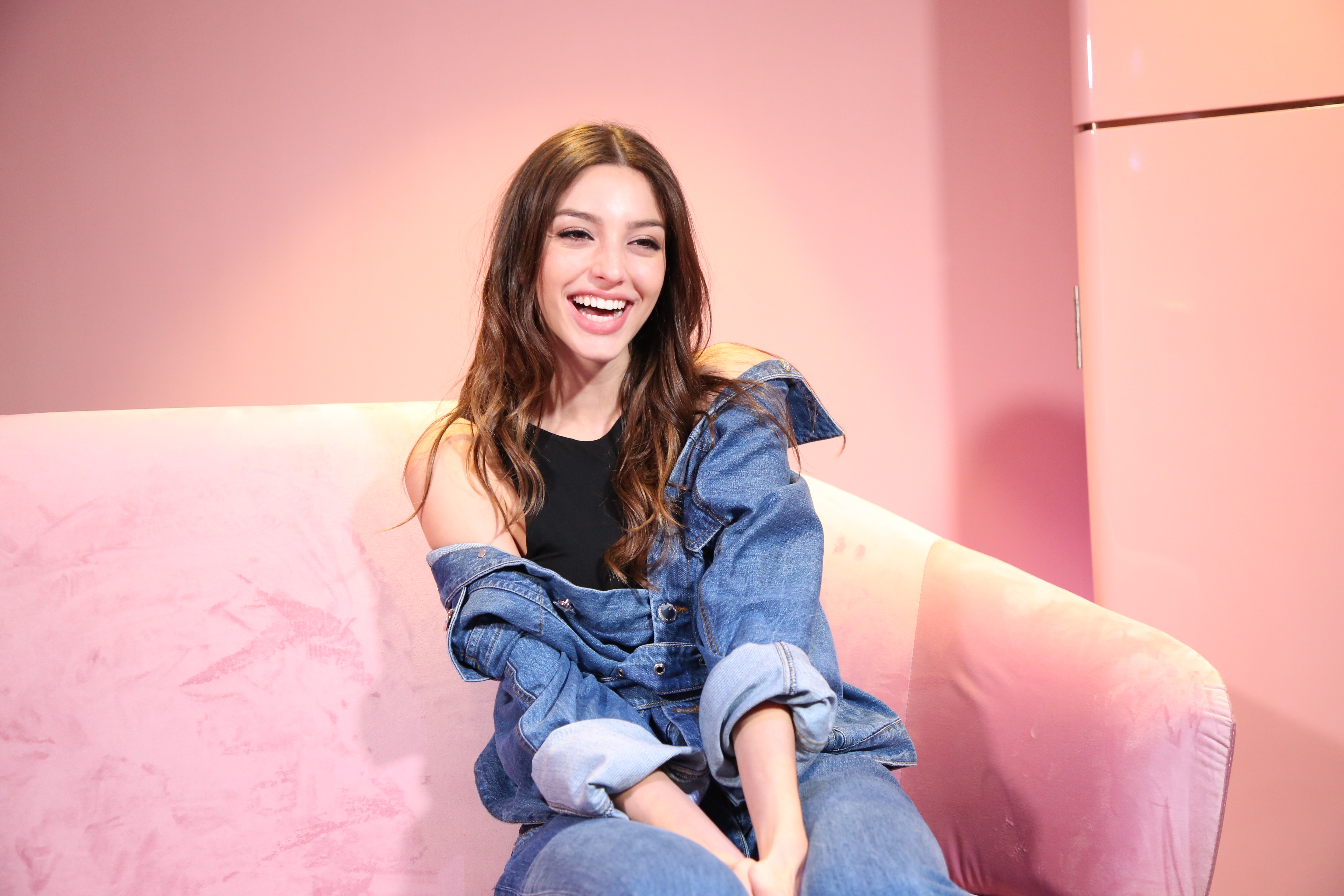 Celine Farach smiling on a pink couch HD Wallpaper