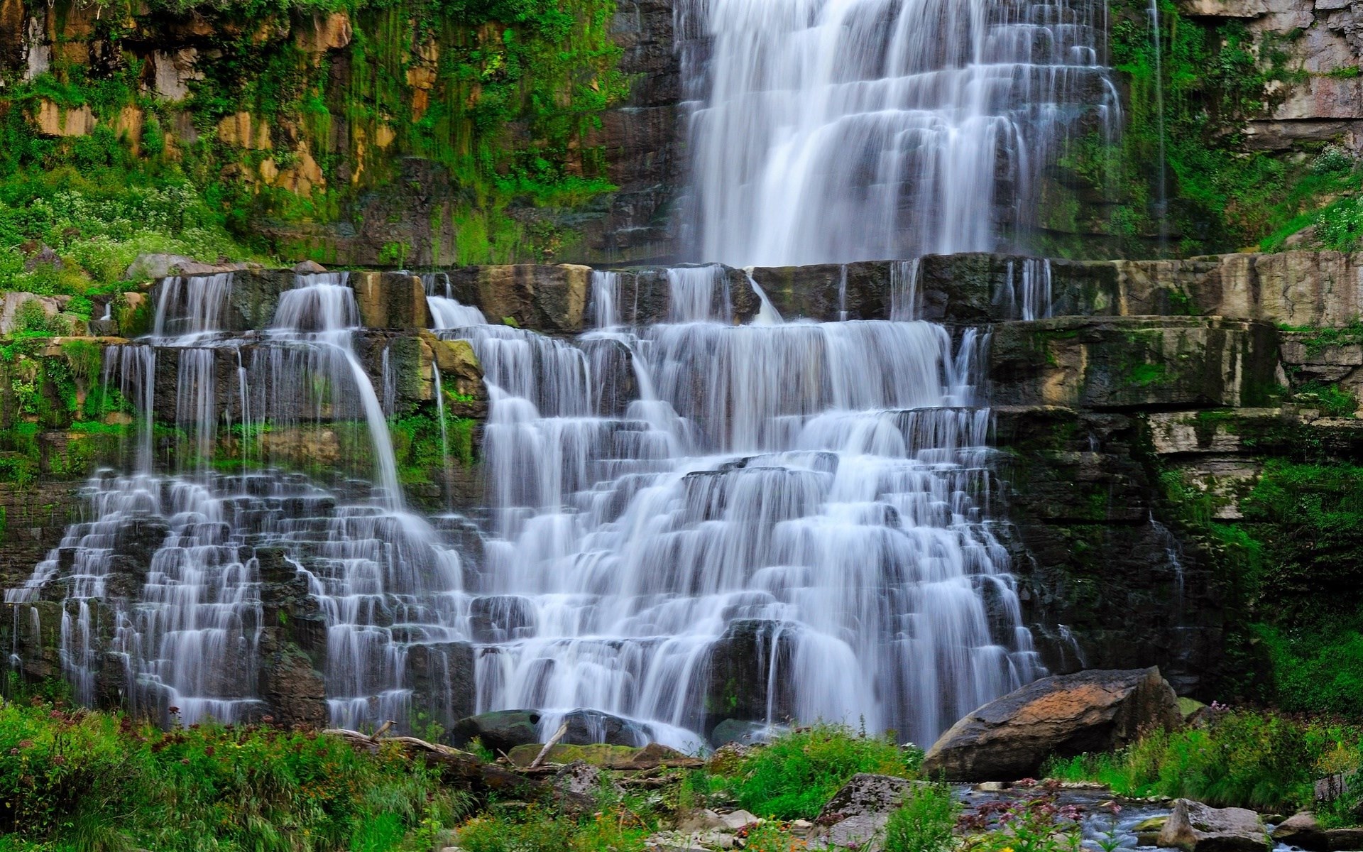 Multi-tiered waterfall cascading over mossy rocks HD Wallpaper