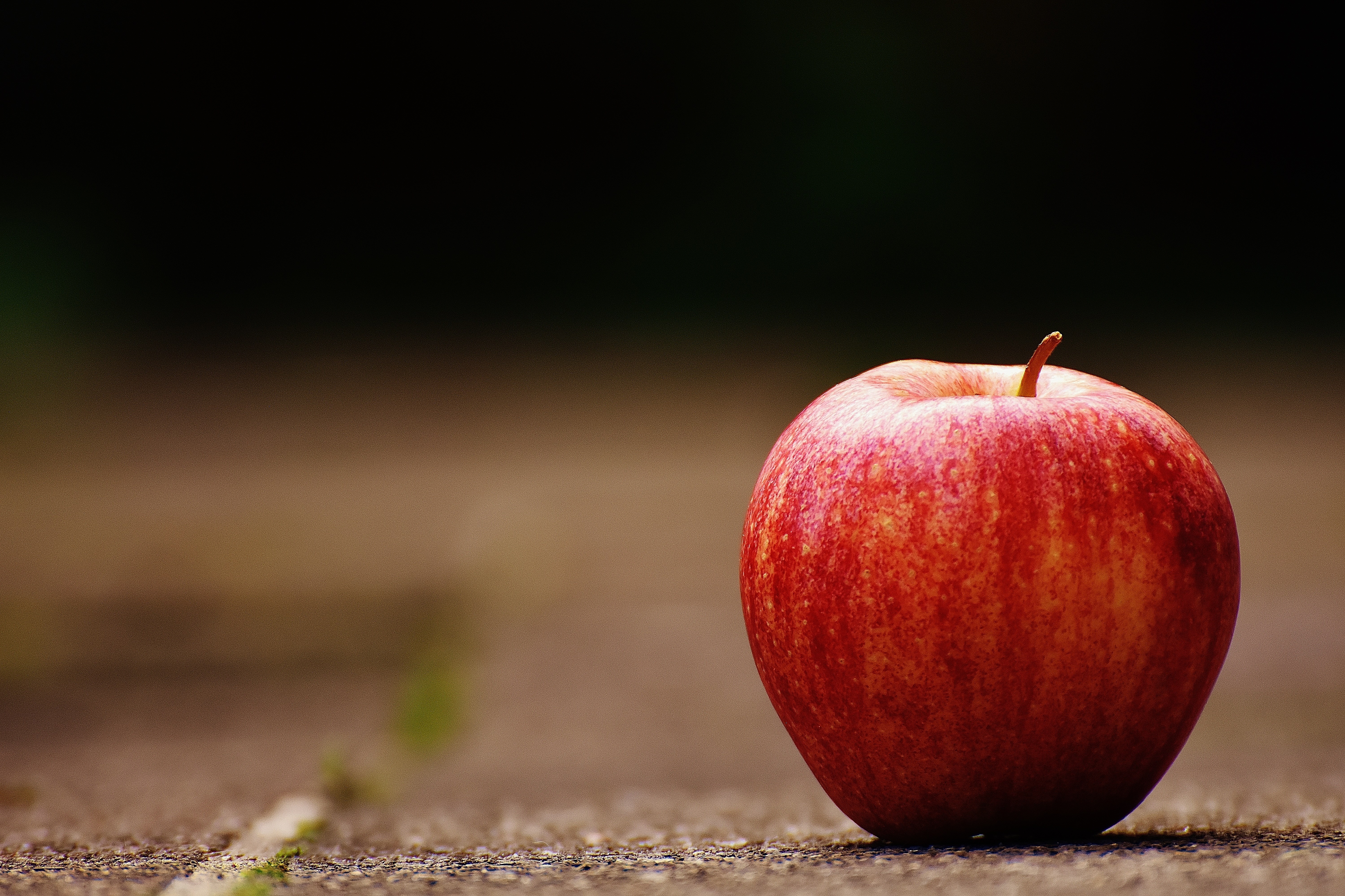 Red apple on a textured surface HD Wallpaper
