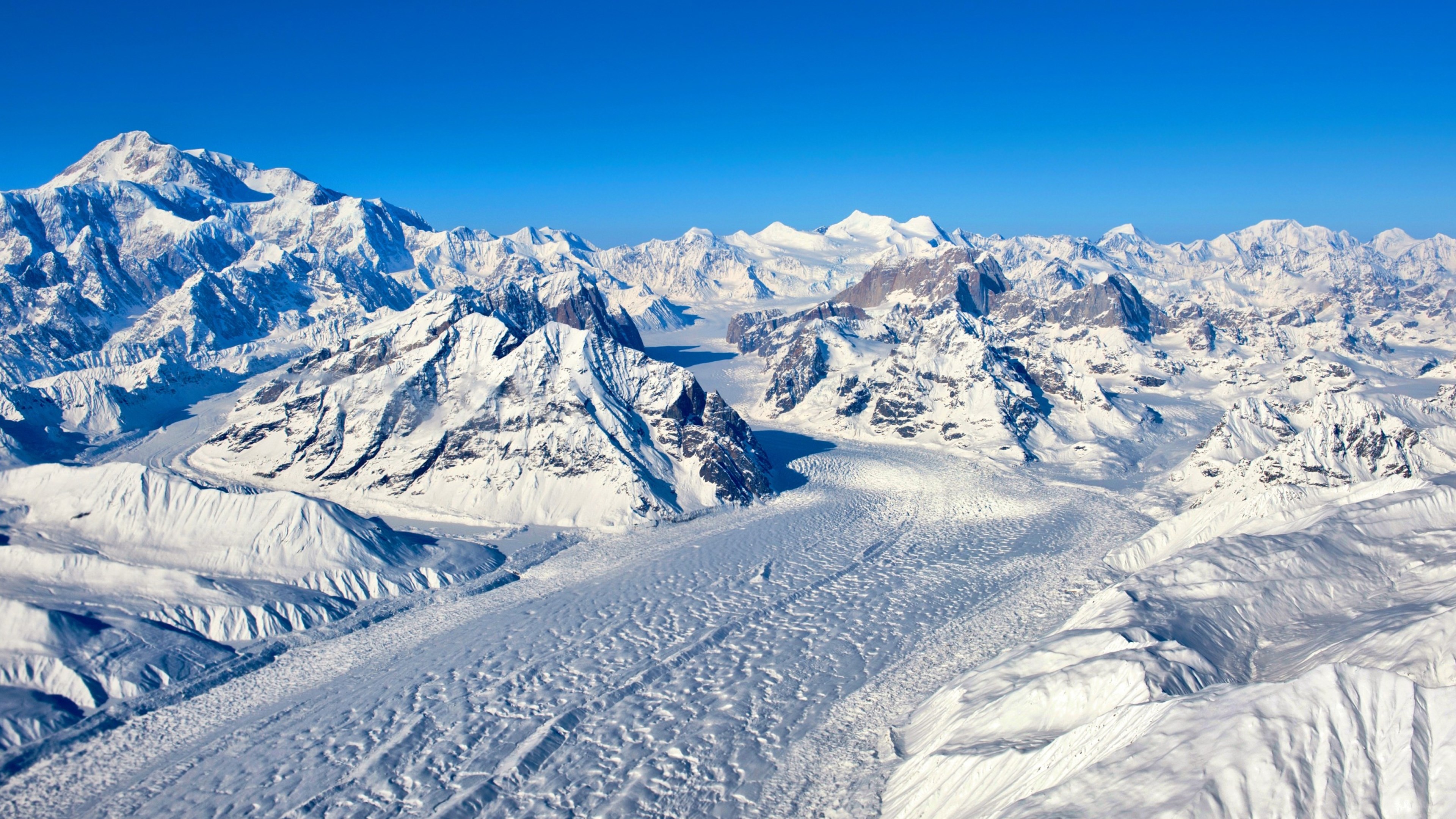 Snowy mountain range with glaciers under a clear blue sky HD Wallpaper