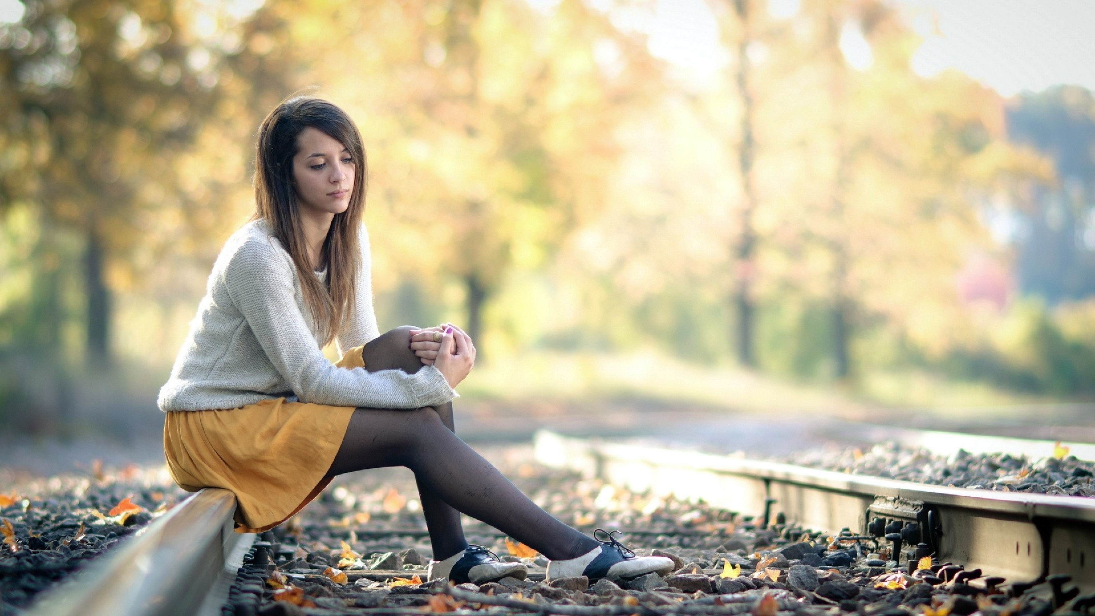 Woman Sitting Thoughtfully on Railroad Track in 4K HD Wallpaper