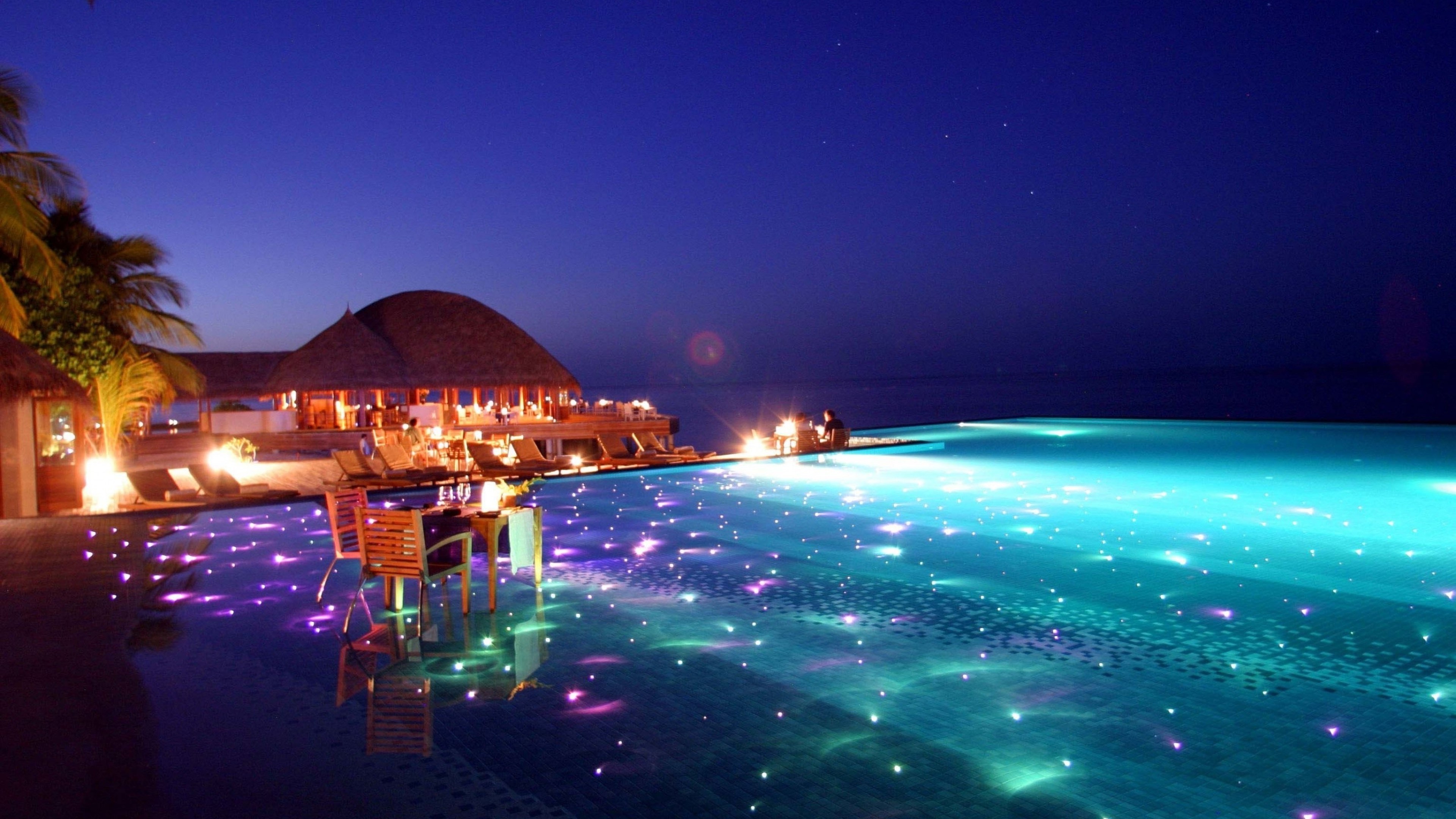Infinity pool at a resort at night HD Wallpaper