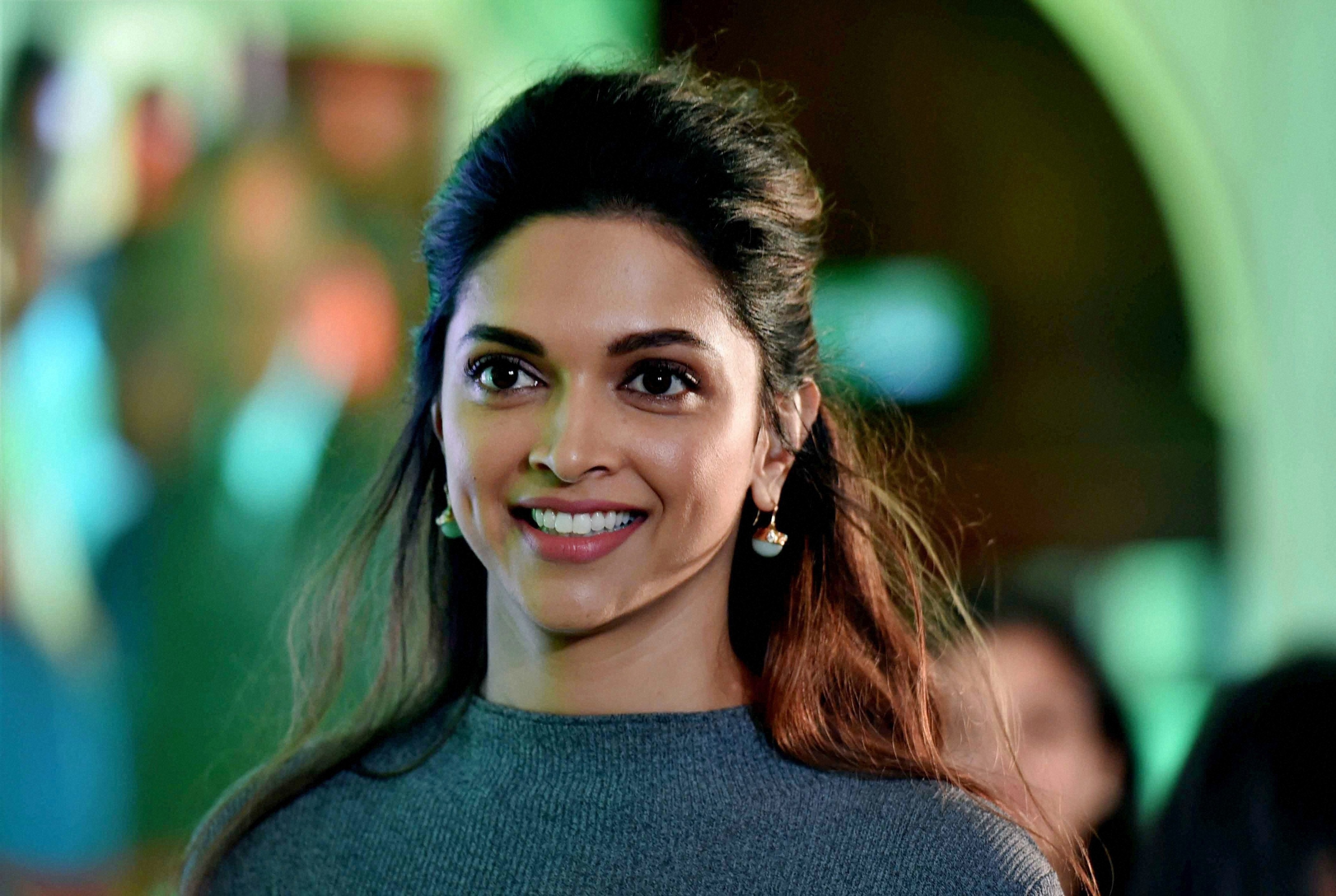 Deepika Padukone smiling in a grey sweater HD Wallpaper