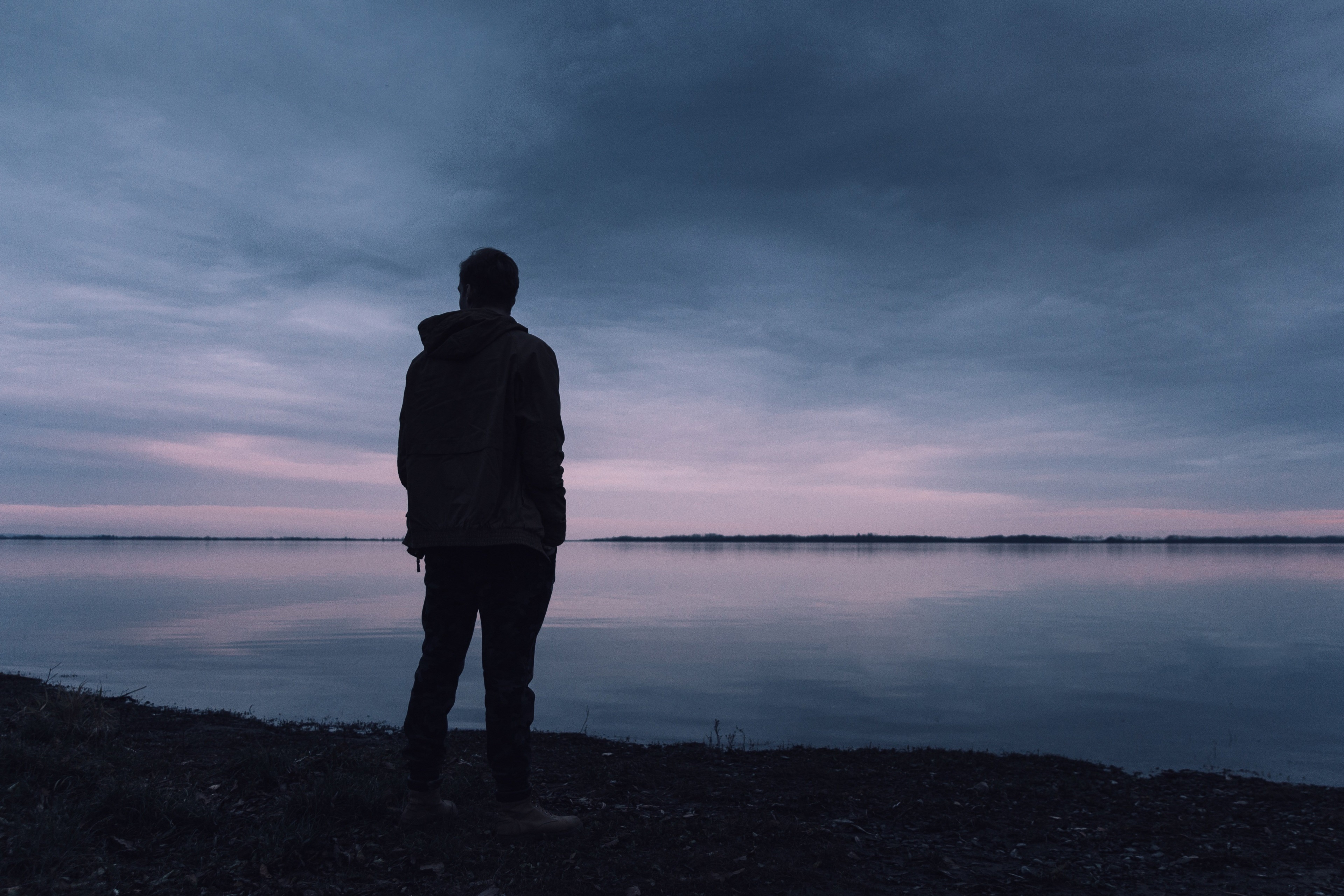 Man standing by a lake at dusk HD Wallpaper
