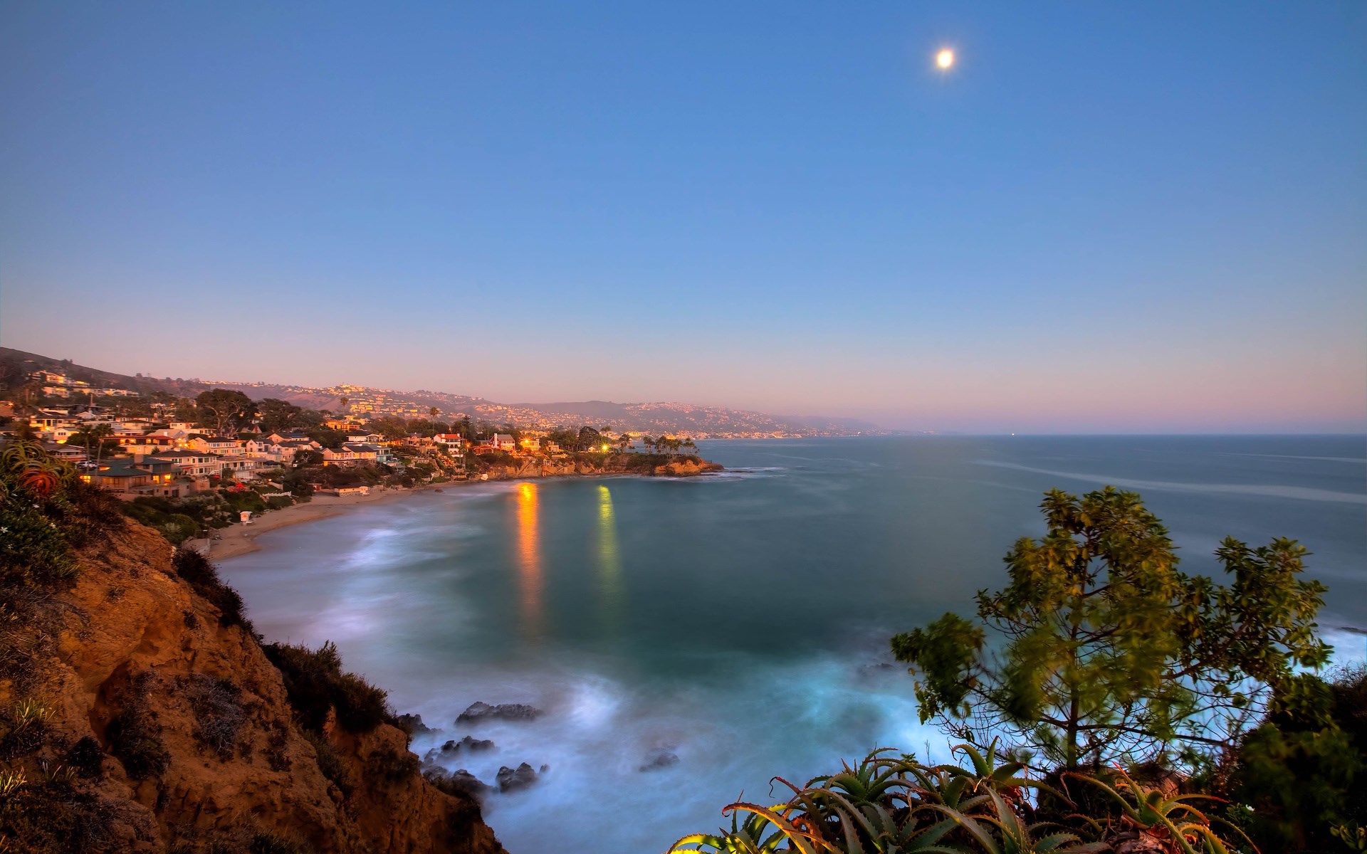 Coastal town at dusk with moon over the ocean HD Wallpaper