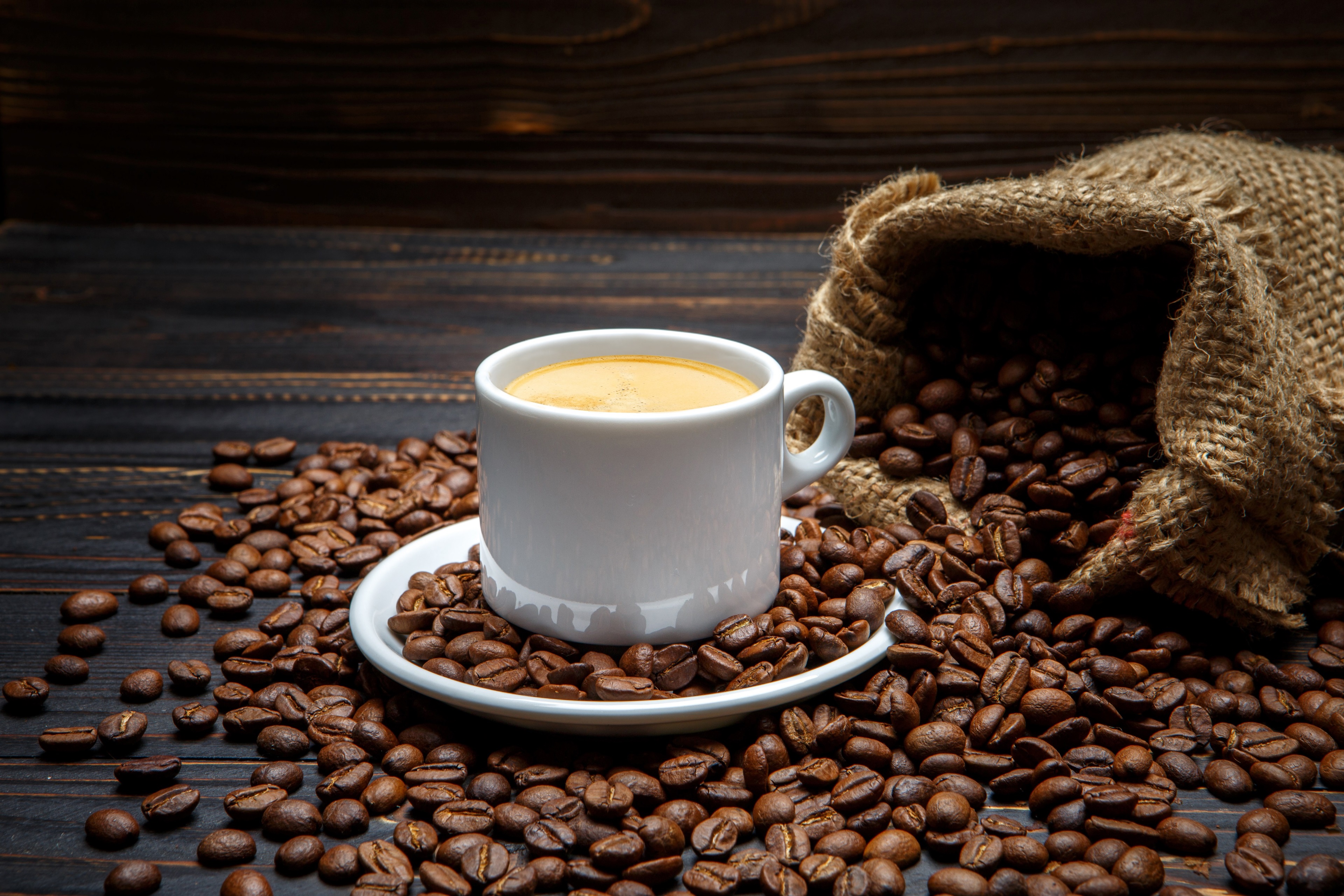 Coffee cup and beans on wooden table 4K HD Wallpaper