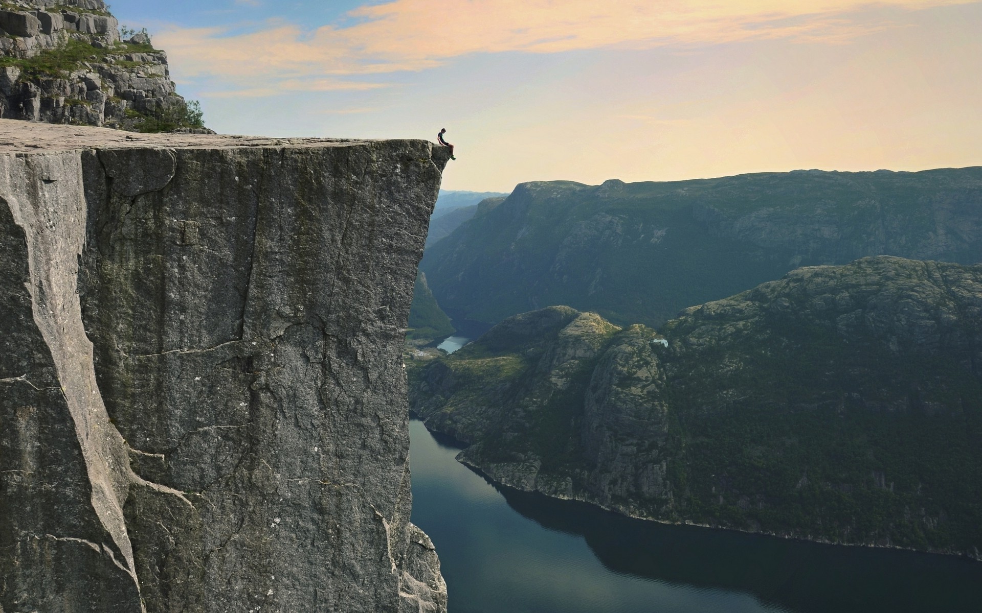 Person sitting on Preikestolen cliff overlooking Lysefjord, Norway HD Wallpaper