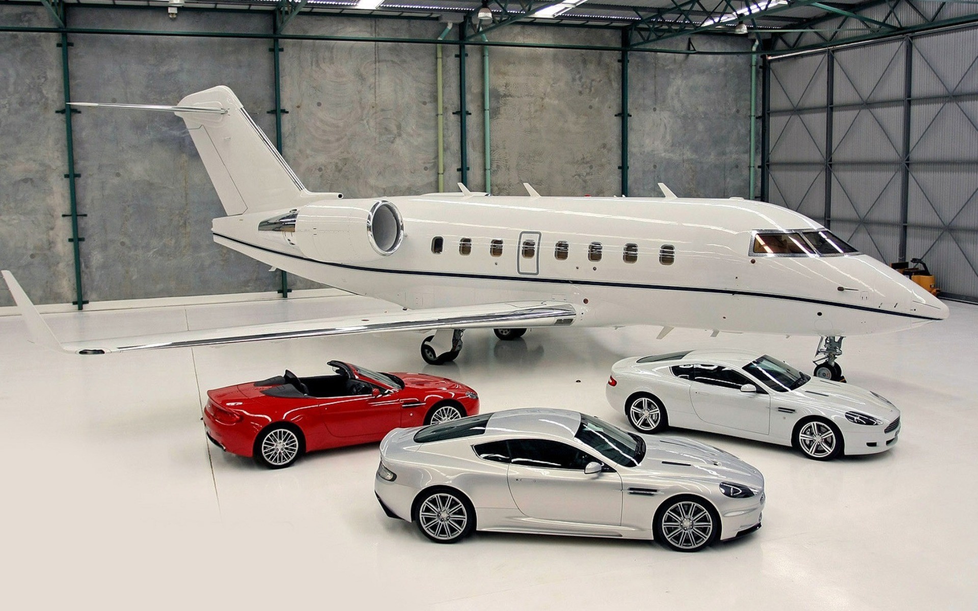 Private jet with Aston Martin sports cars in hangar HD Wallpaper