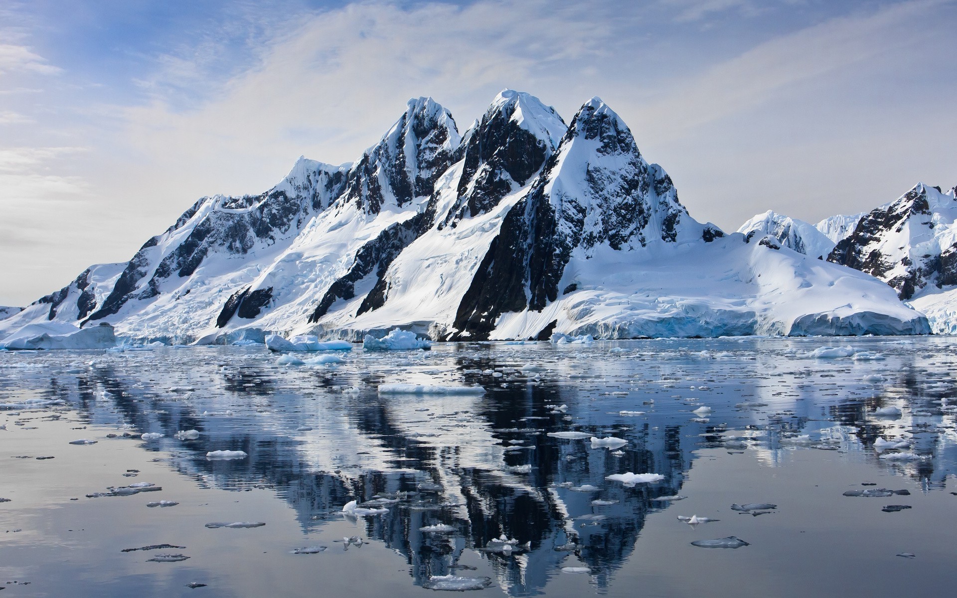 Snow-covered mountains reflected in icy water HD Wallpaper