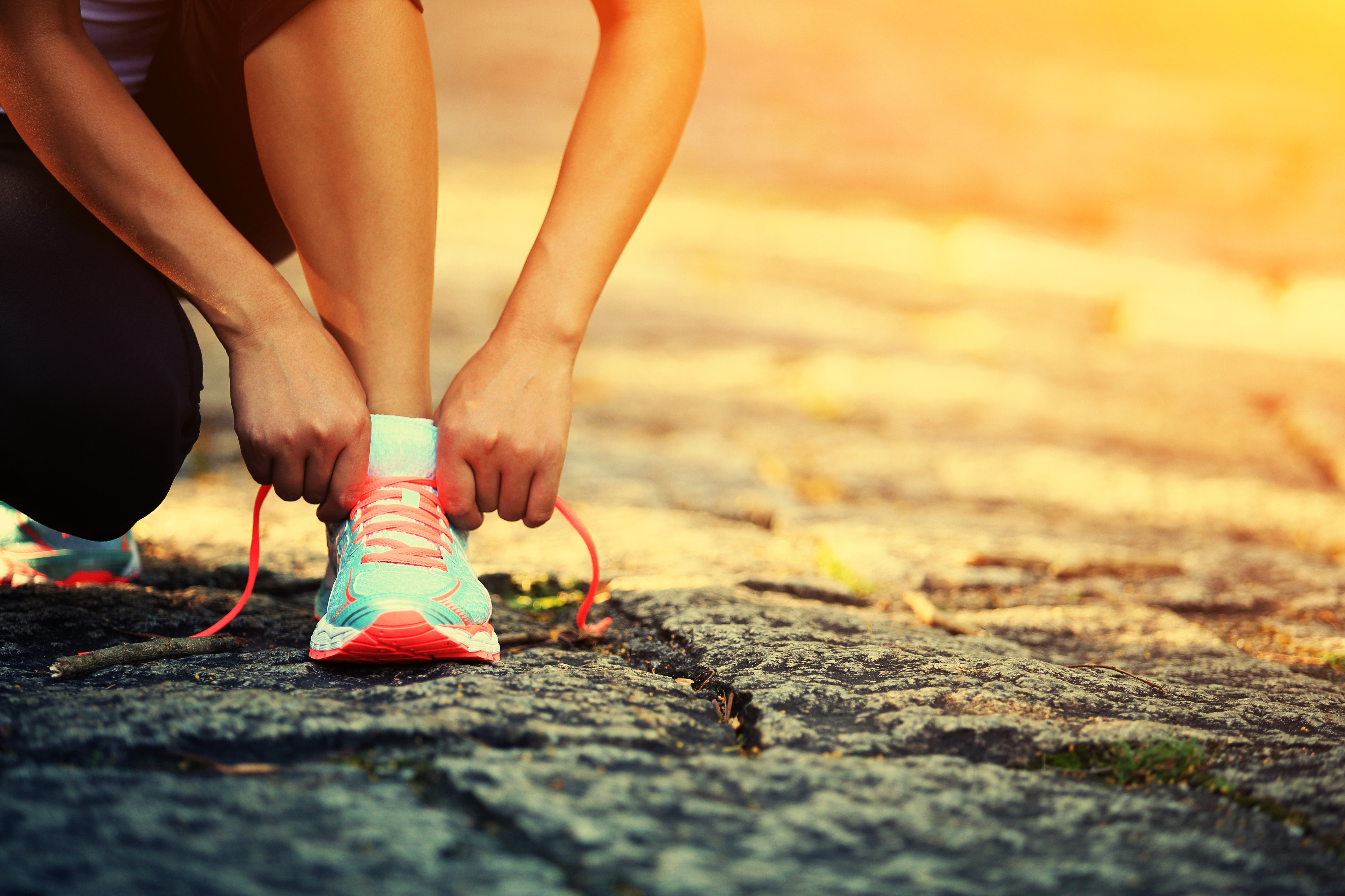 Person tying running shoe laces on asphalt path HD Wallpaper
