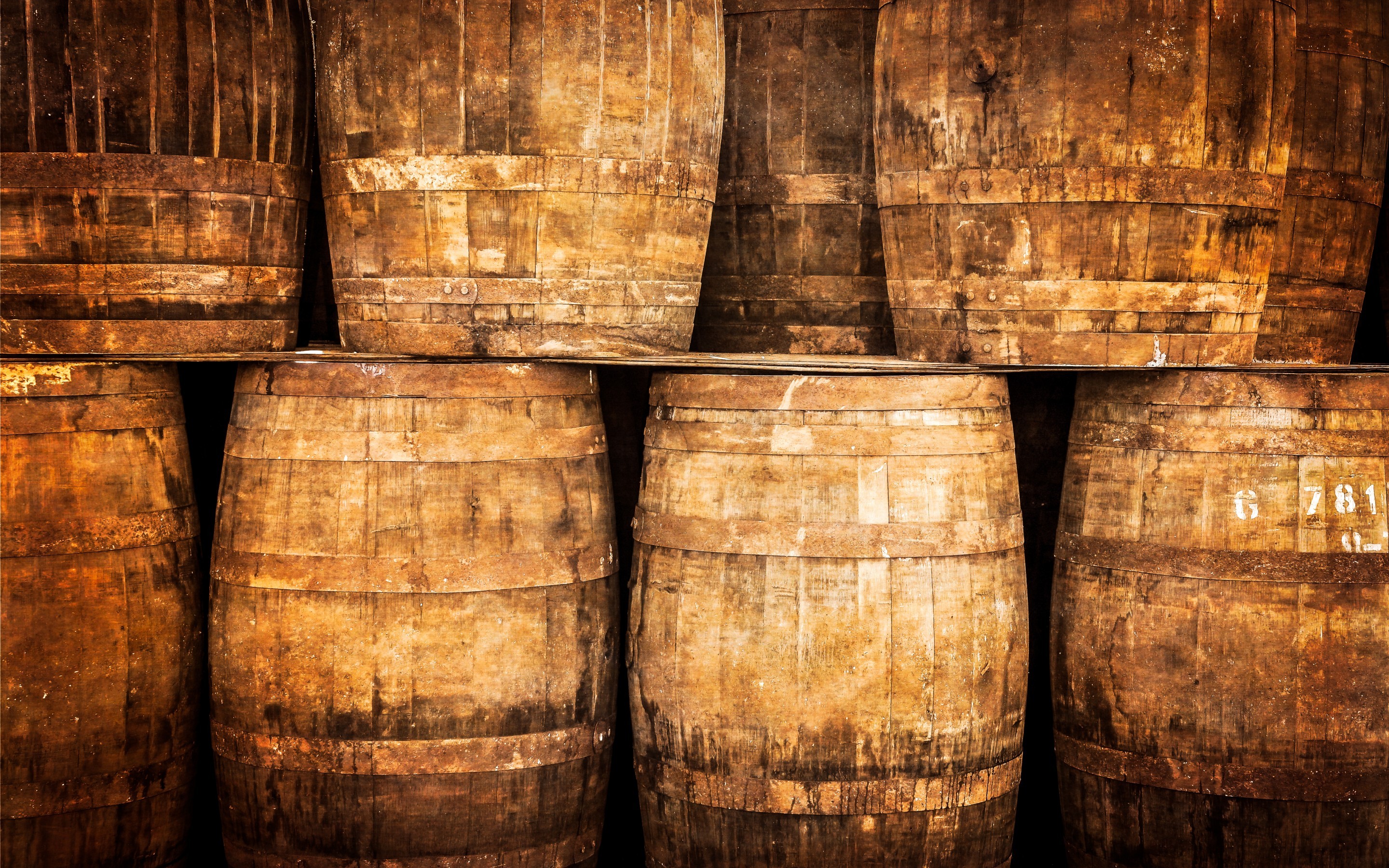 Stacked wooden whisky barrels in a cellar HD Wallpaper
