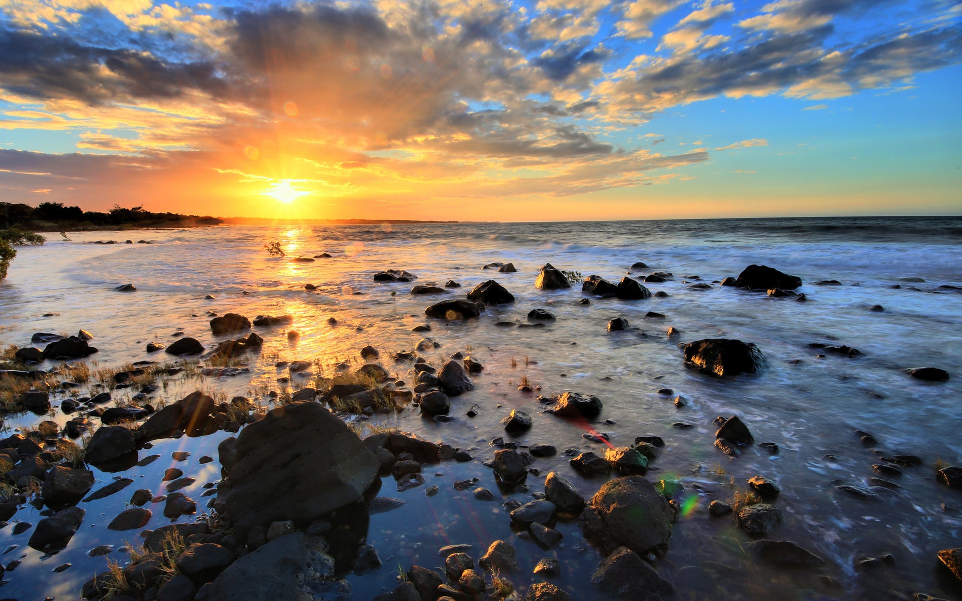 Sunset over a rocky beach with waves HD Wallpaper