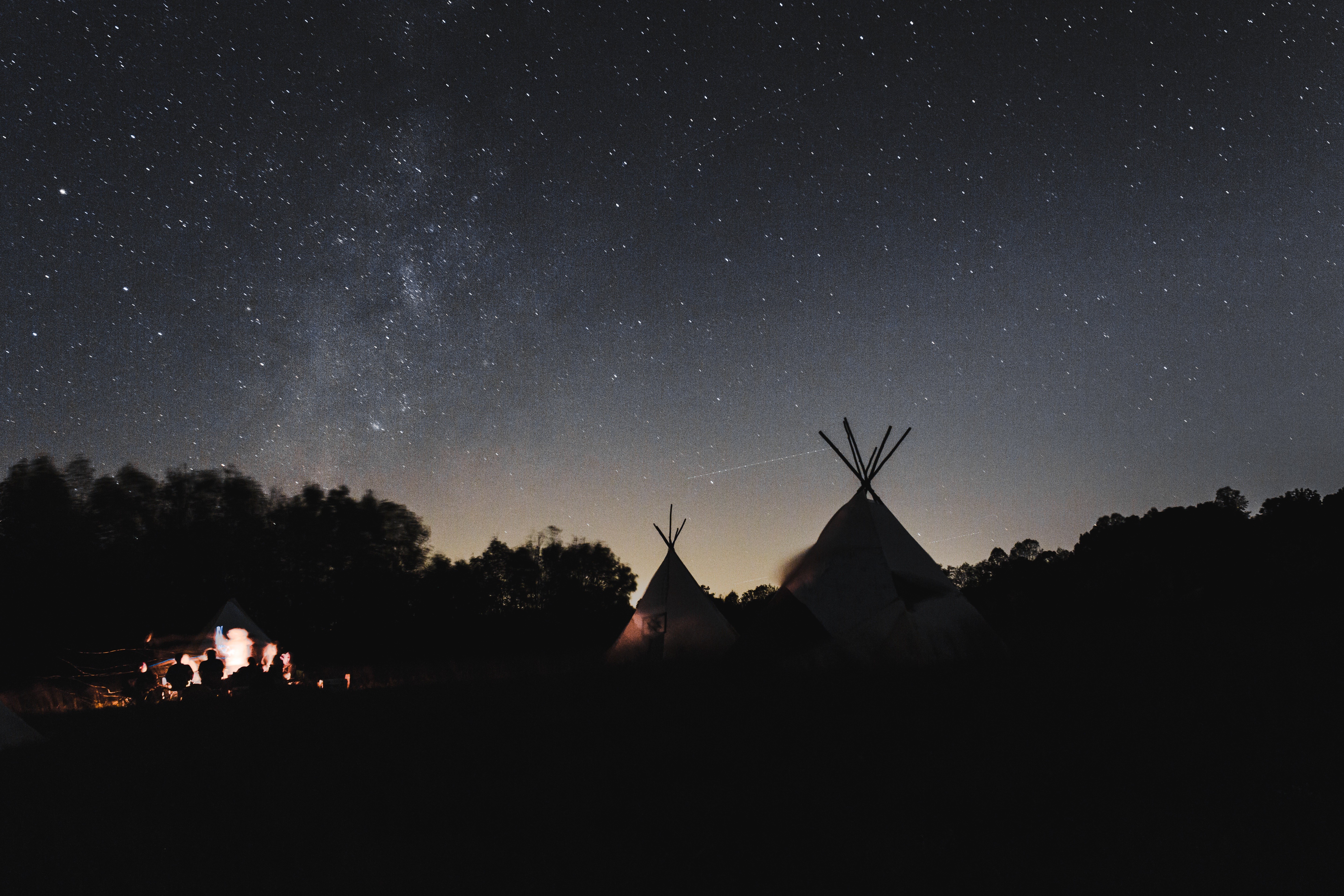 Tipi camp under a starry night sky HD Wallpaper