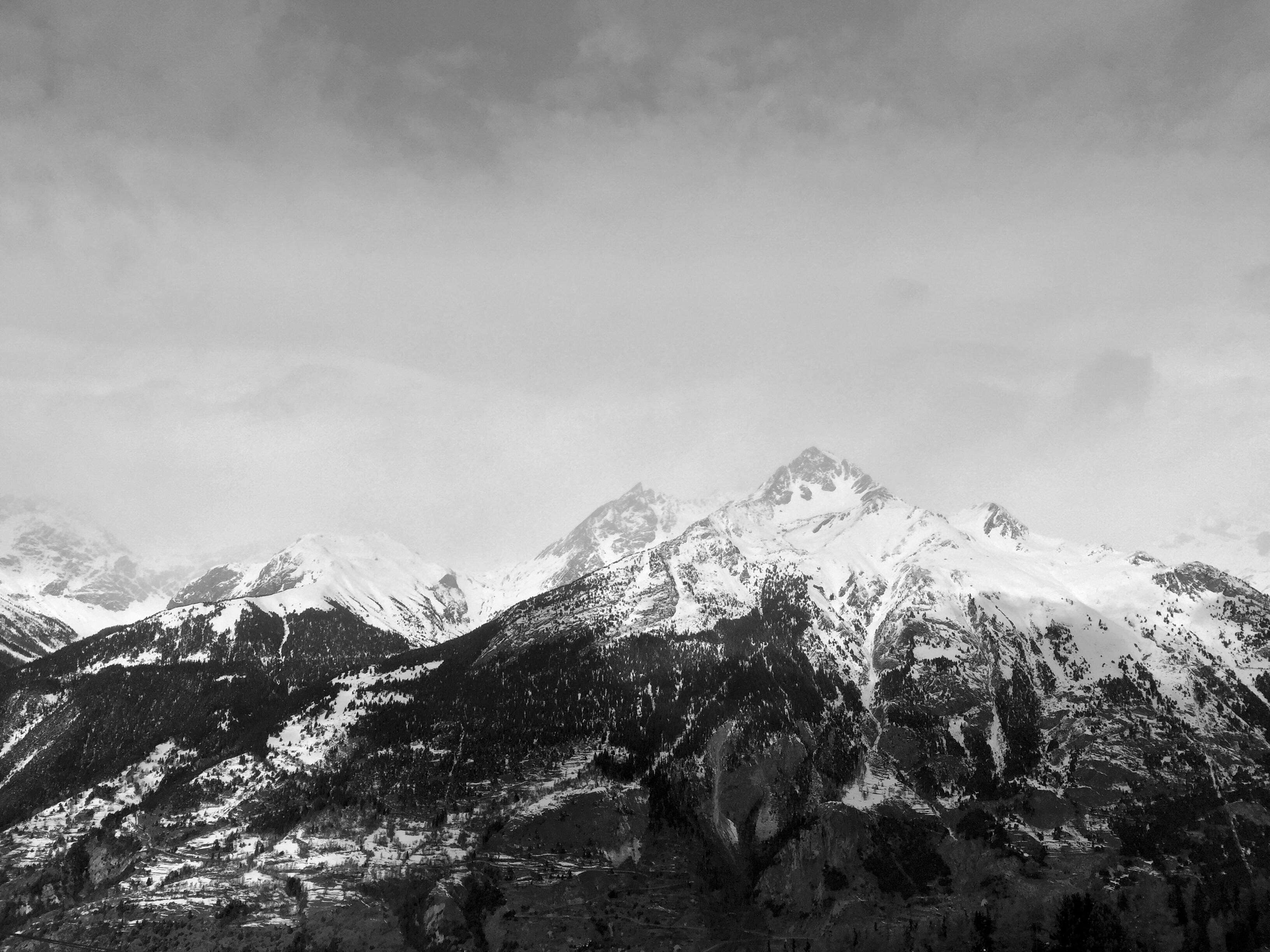 Snow-covered mountains under a cloudy sky HD Wallpaper