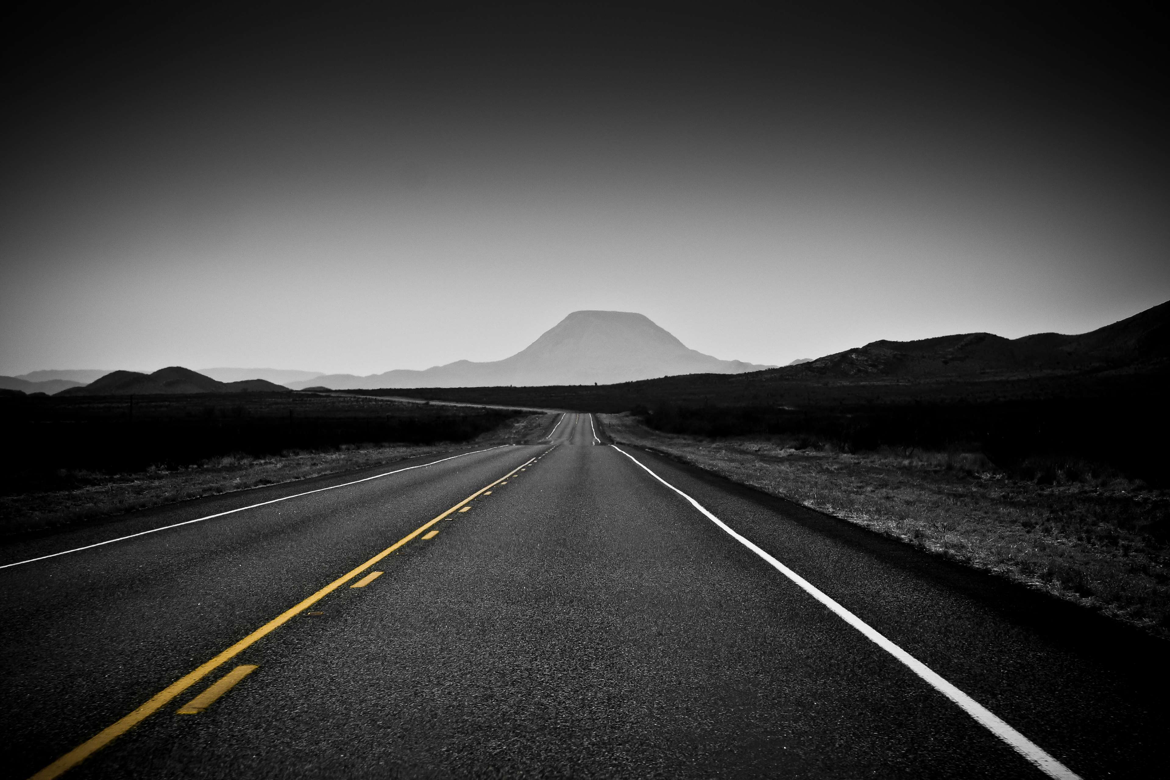 Desert road leading to a mountain in black and white 4K HD Wallpaper