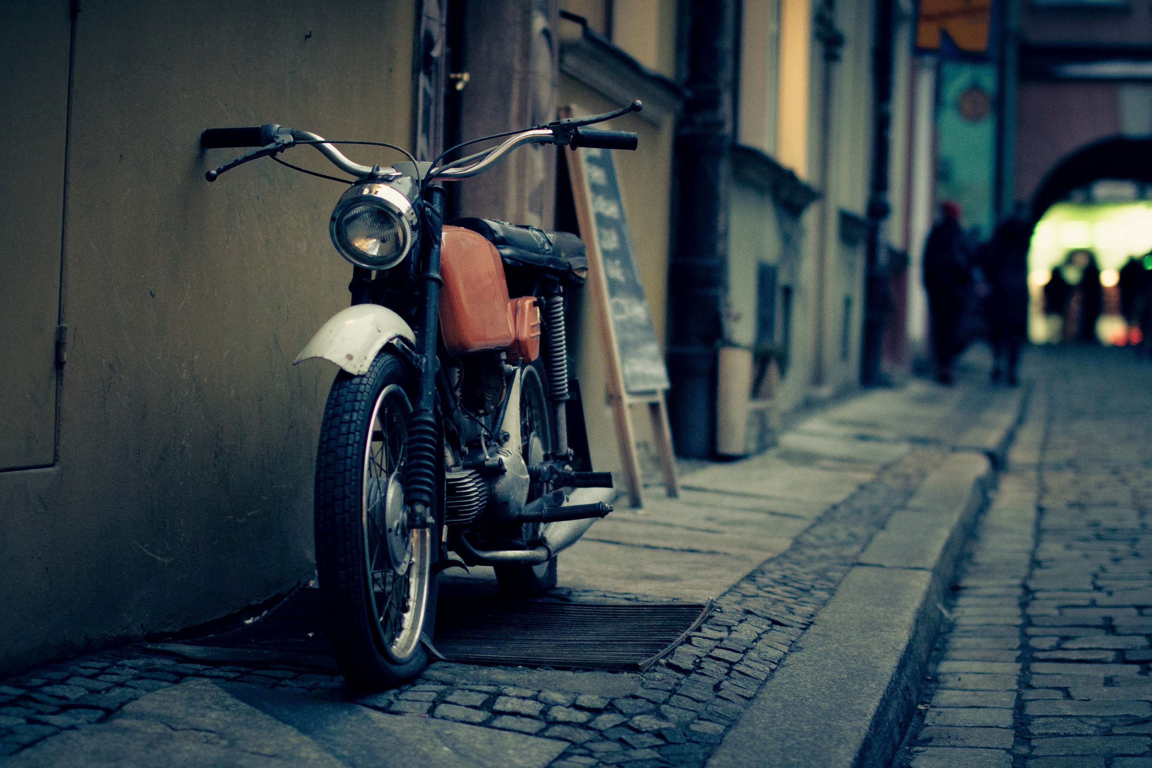 Vintage motorcycle parked on a cobblestone street HD Wallpaper