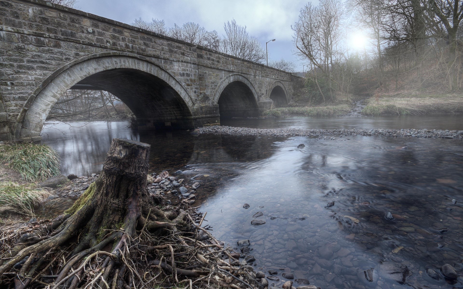 Stone bridge over a river with a tree stump HD Wallpaper
