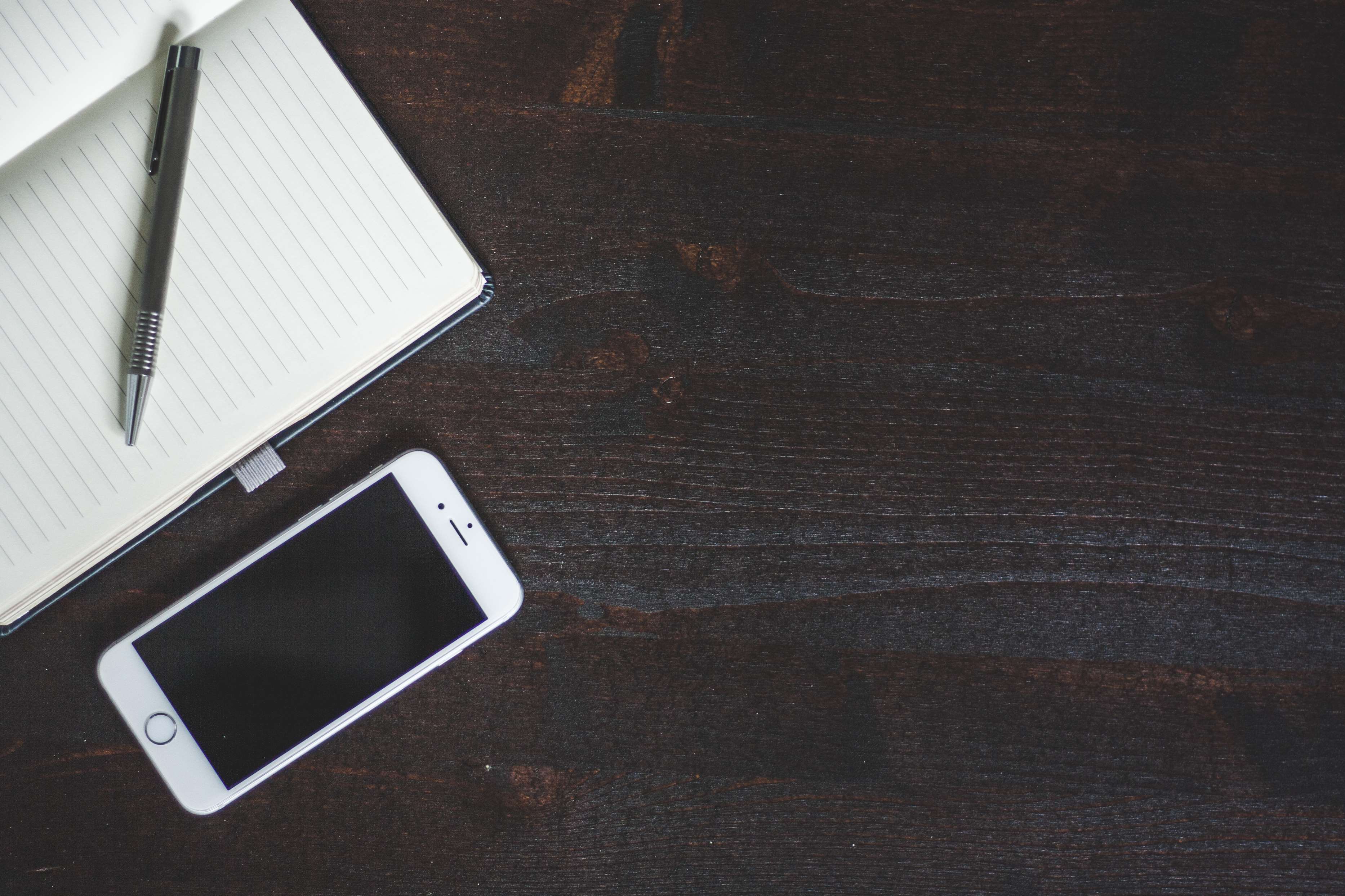 iPhone and notebook on a wooden table HD Wallpaper