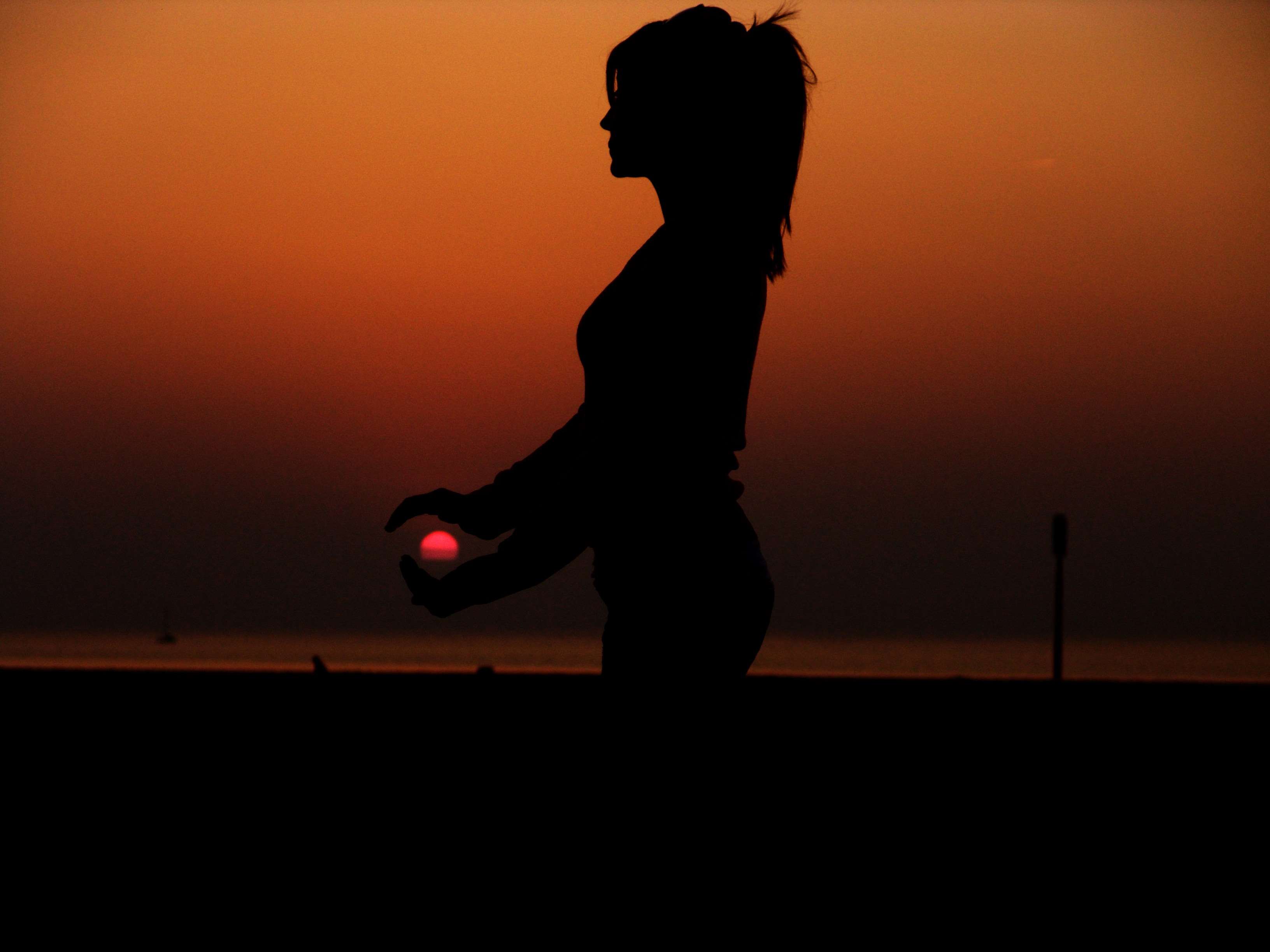 Silhouette of a woman holding the sun at sunset HD Wallpaper