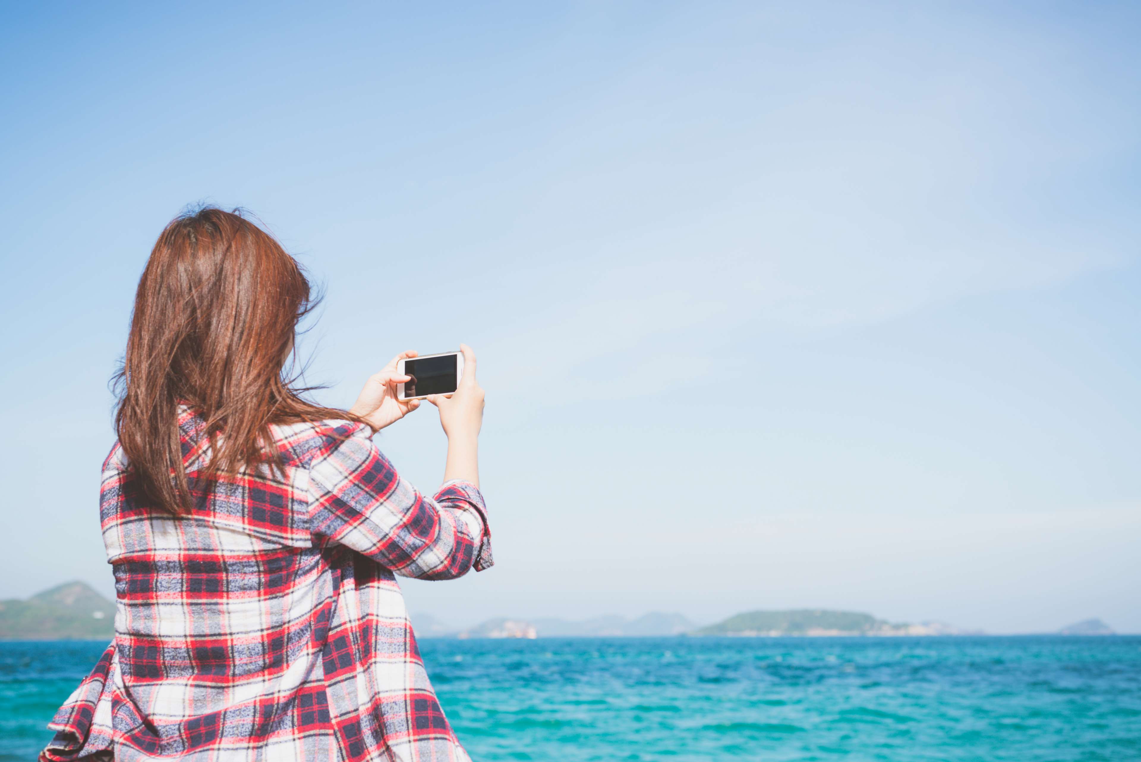 Woman in Plaid Shirt Taking Photo of Ocean HD Wallpaper