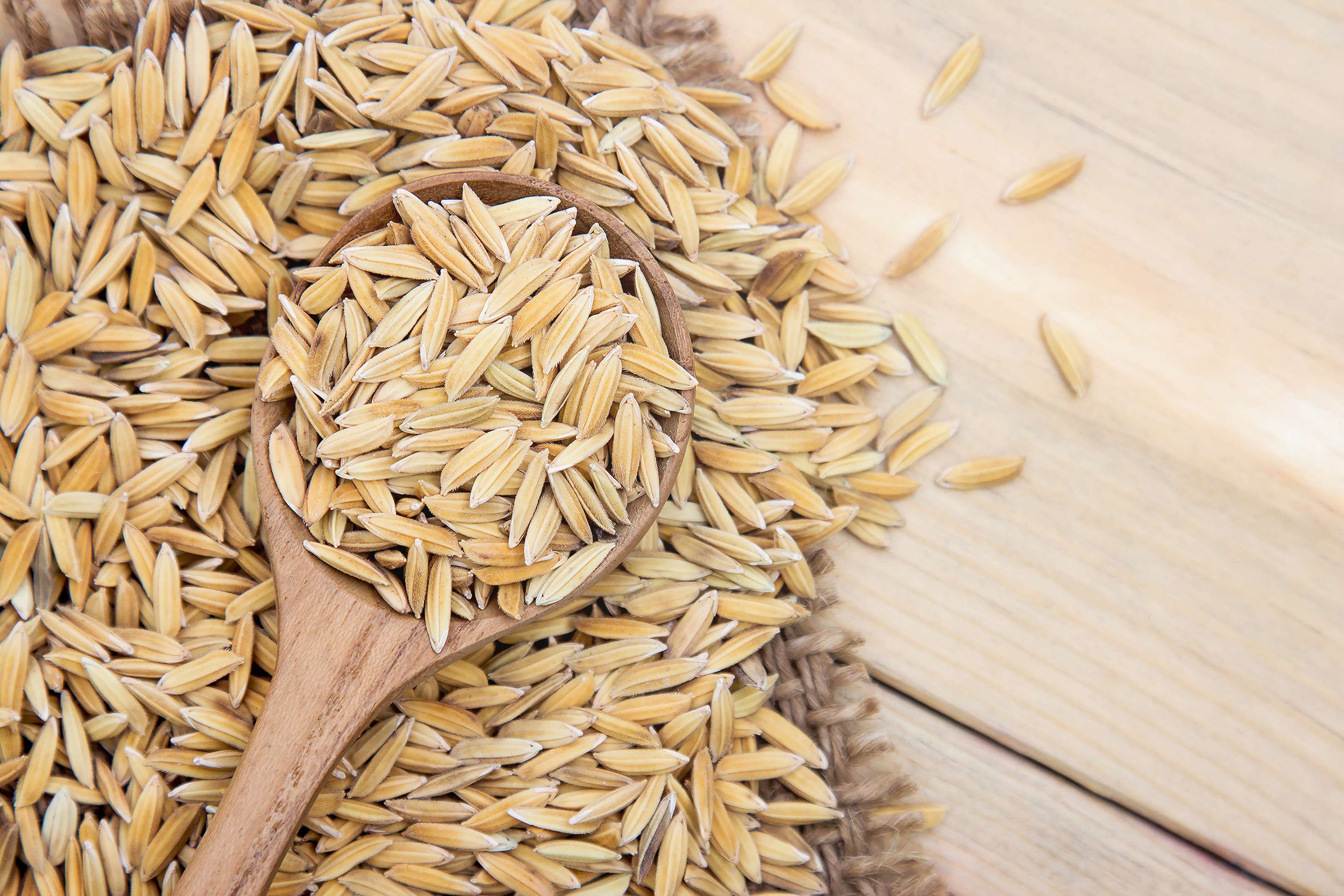 Paddy rice in a wooden spoon on a table HD Wallpaper