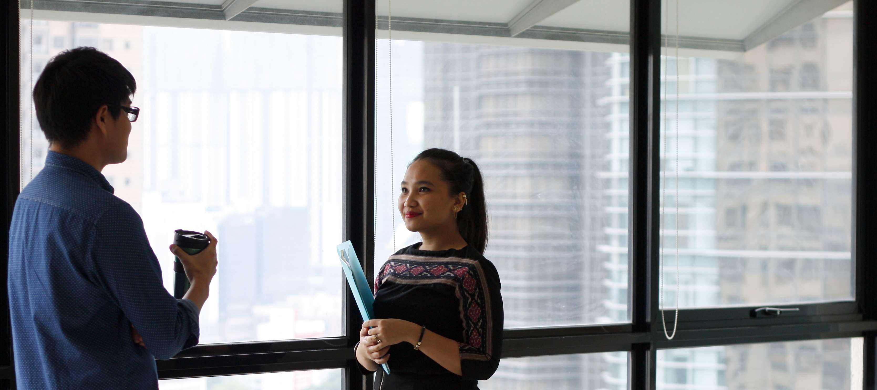 Coworkers discussing by the office window HD Wallpaper