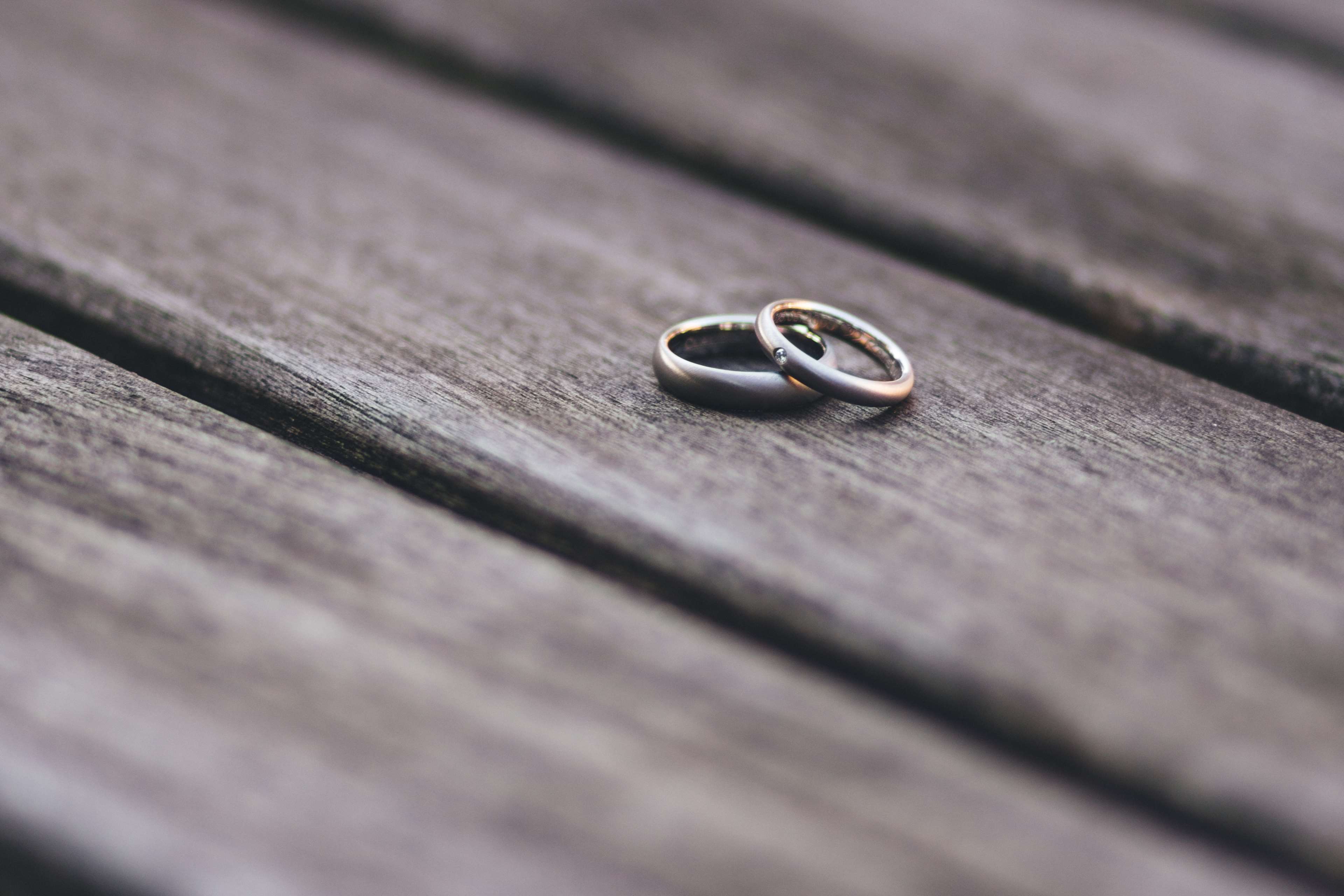 Two wedding rings on a wooden table HD Wallpaper