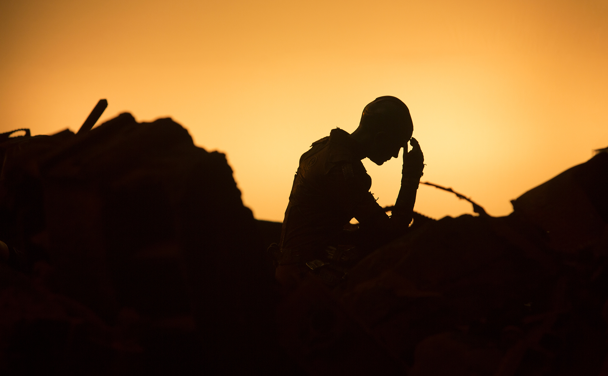 Silhouette of a person with hand on forehead against orange sky HD Wallpaper
