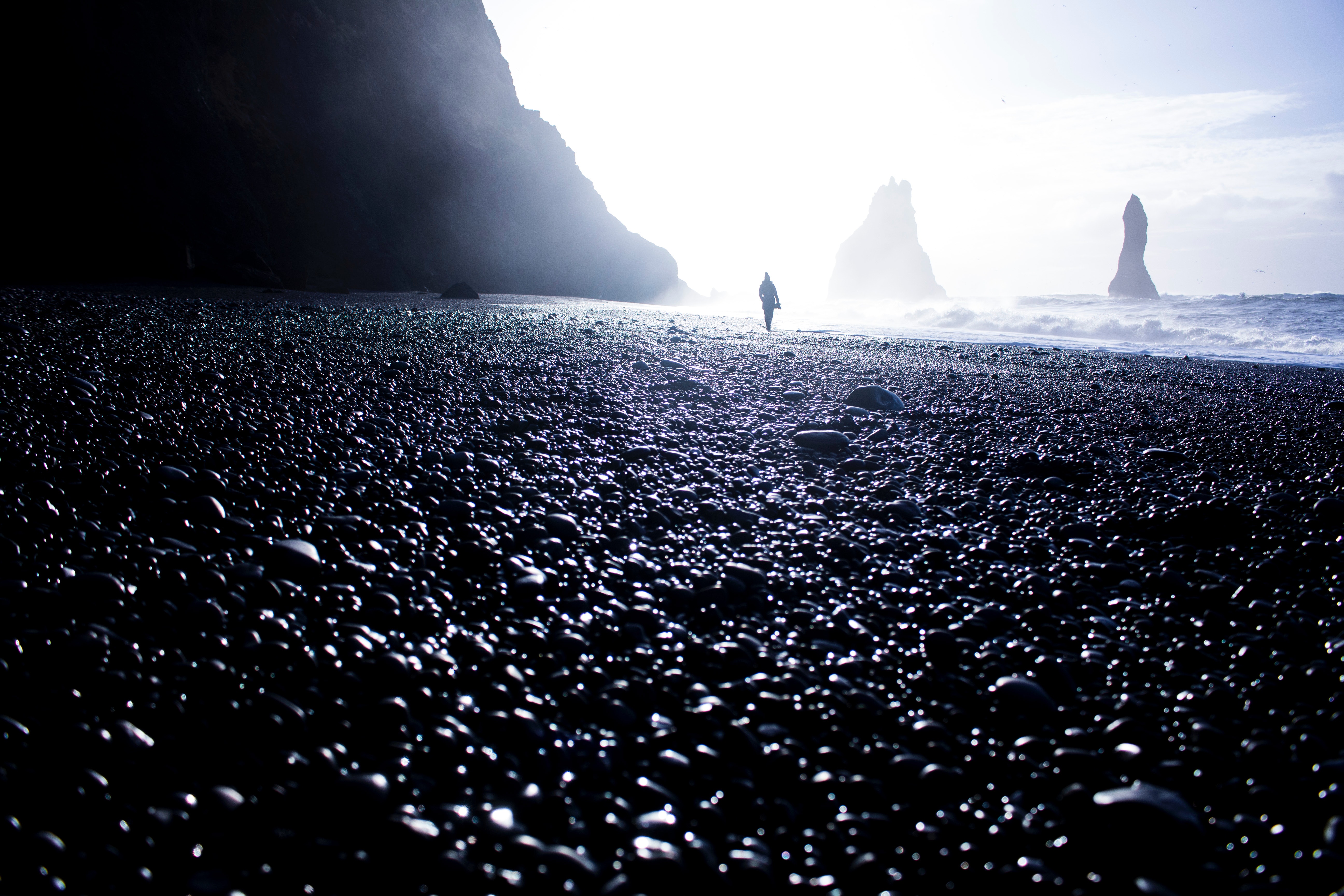 Person walking on a rocky beach with sea stacks HD Wallpaper