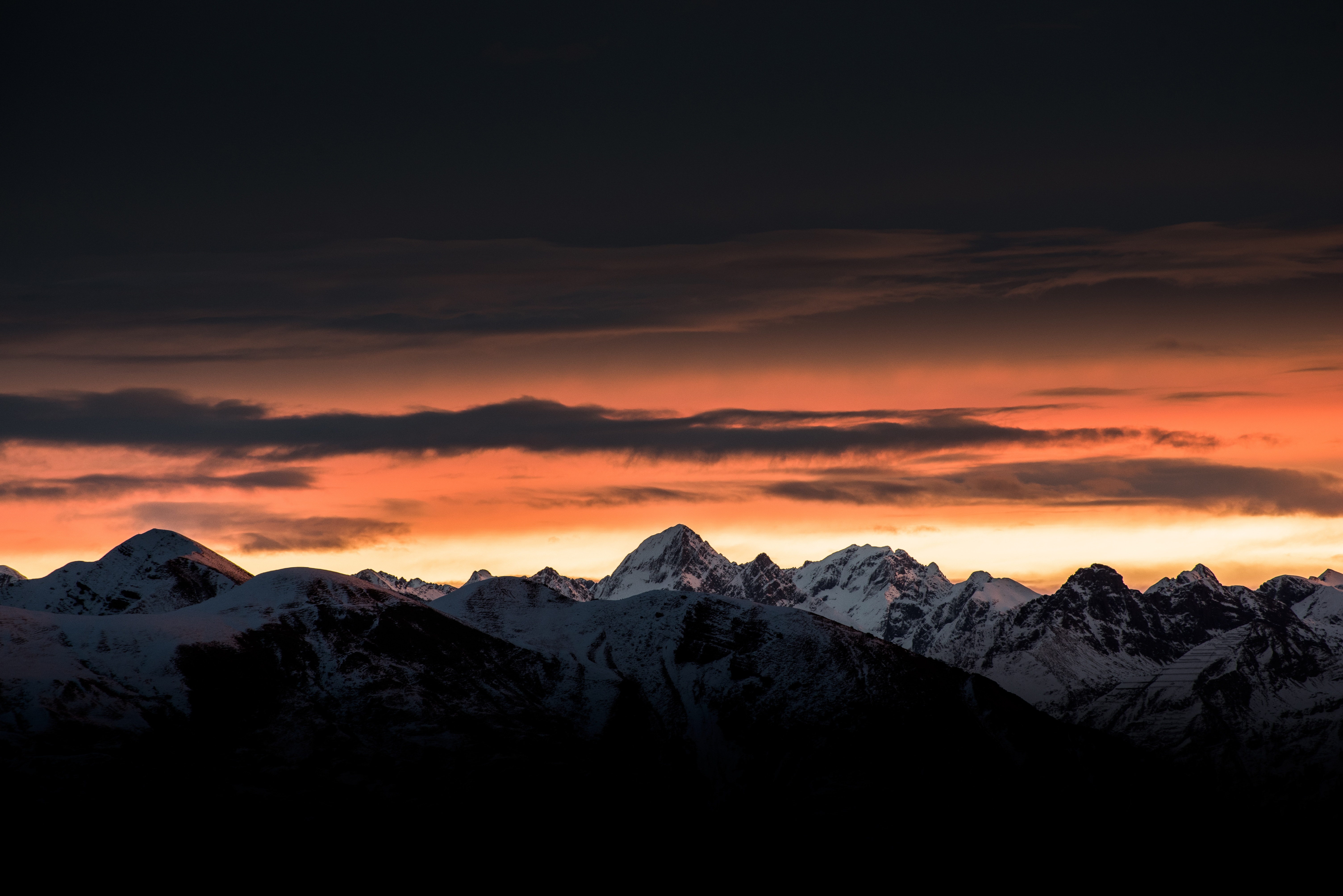 Snow-capped mountains at sunrise with orange clouds HD Wallpaper