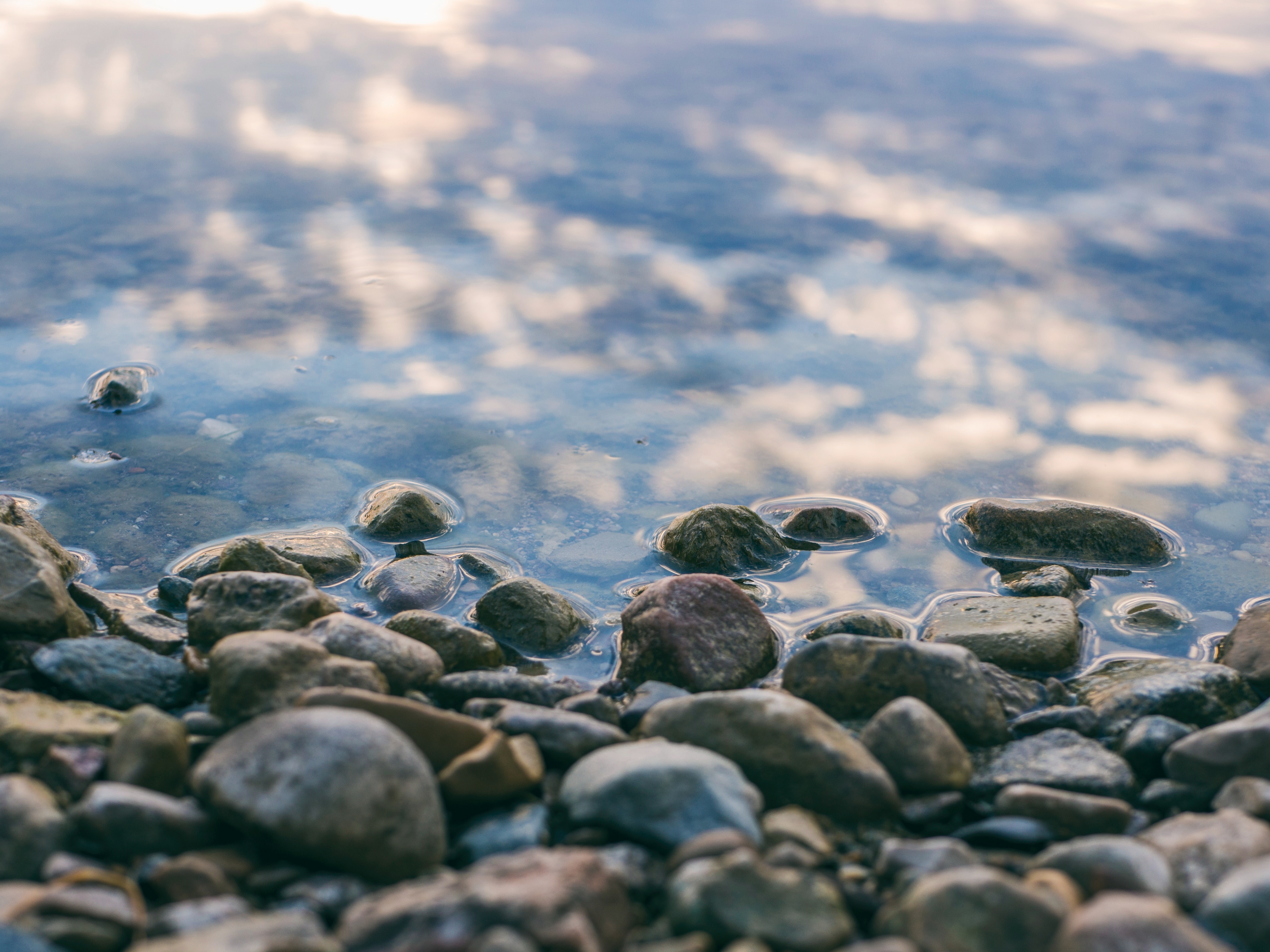 Pebbles on the Shoreline with Water Reflection HD Wallpaper