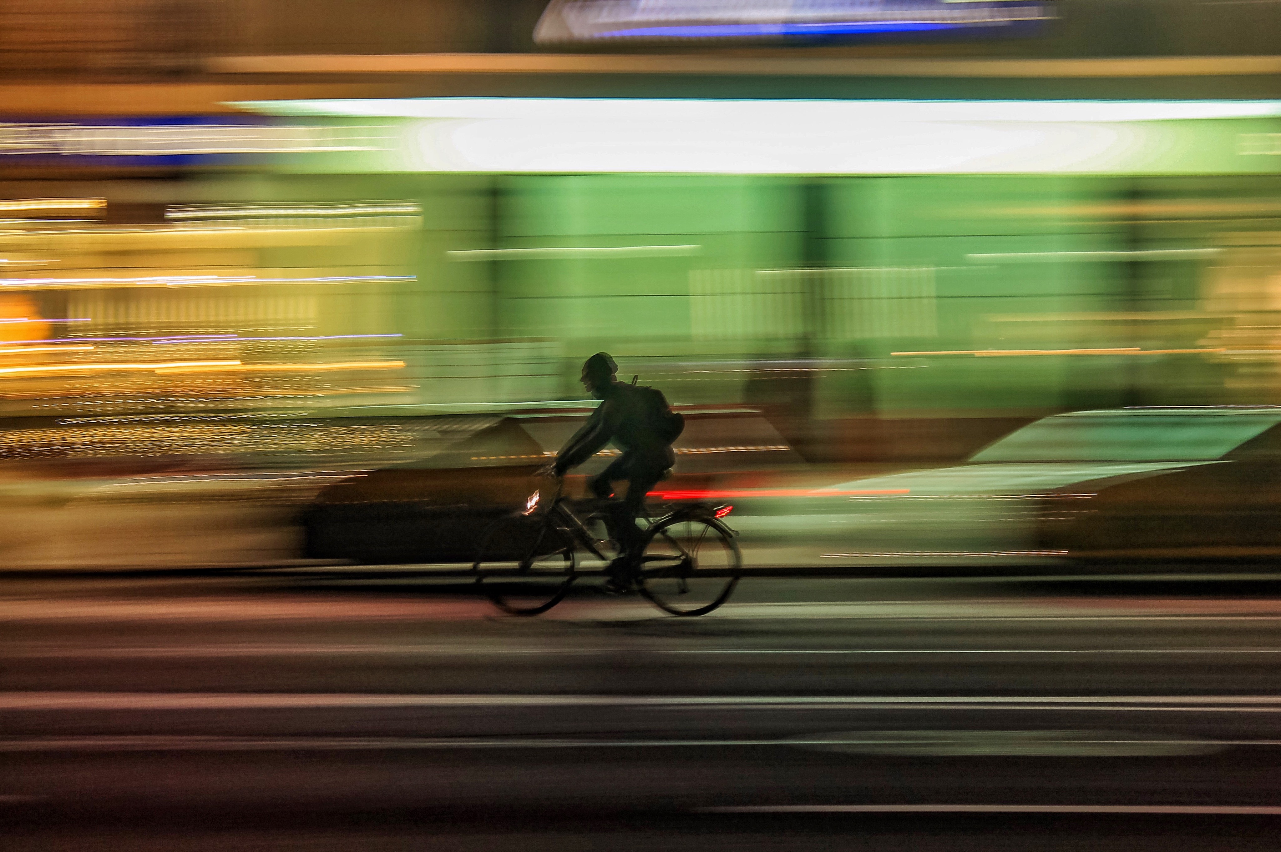 Man cycling on a street at night with long exposure HD Wallpaper