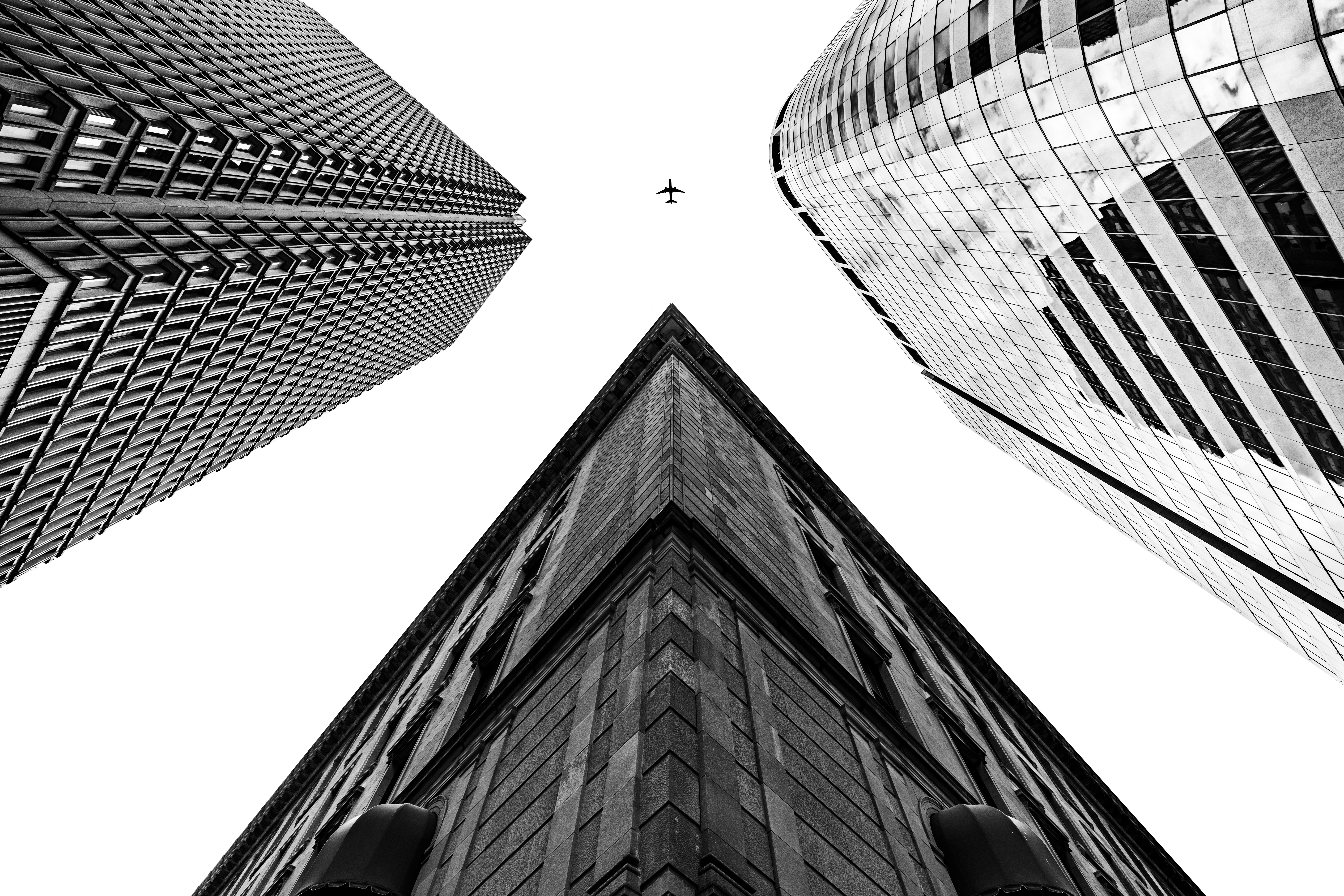 Looking up at skyscrapers with a plane in the sky HD Wallpaper