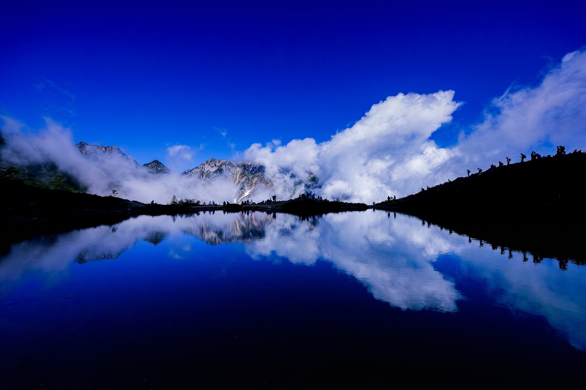 Mountain lake reflection with clouds and hikers HD Wallpaper