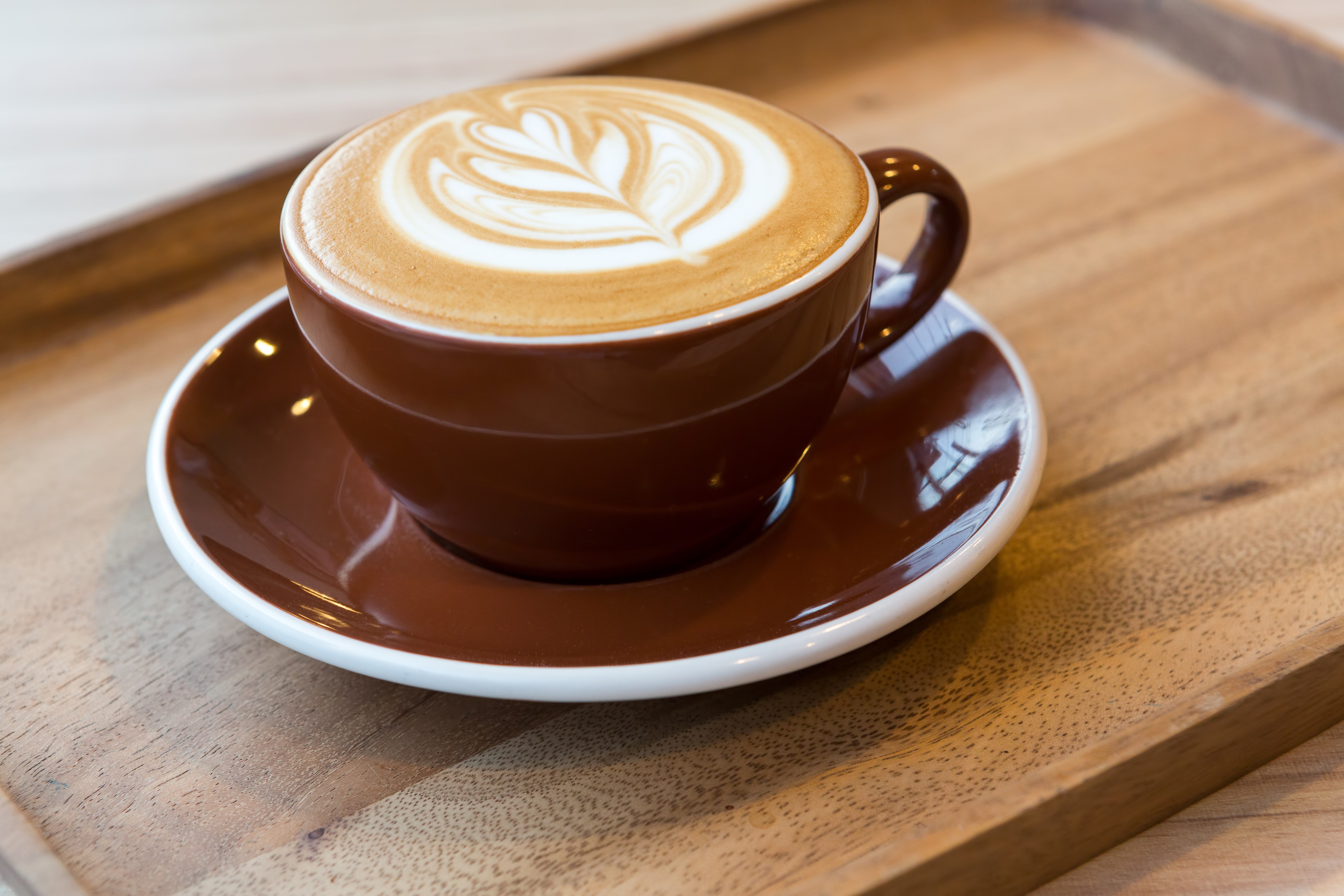 Latte art coffee in a brown cup on a wooden tray HD Wallpaper